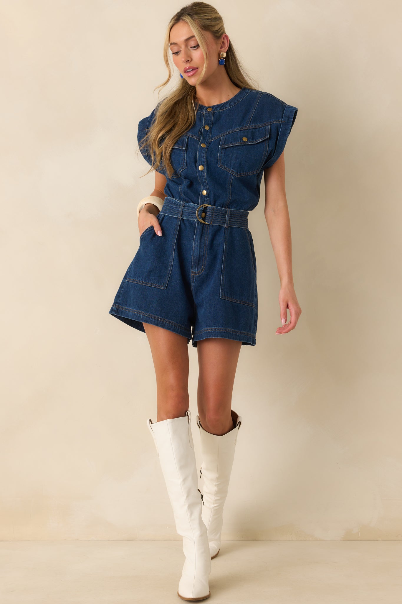 A full body image highlighting the denim romper with tan stitch detailing and functional front pockets.