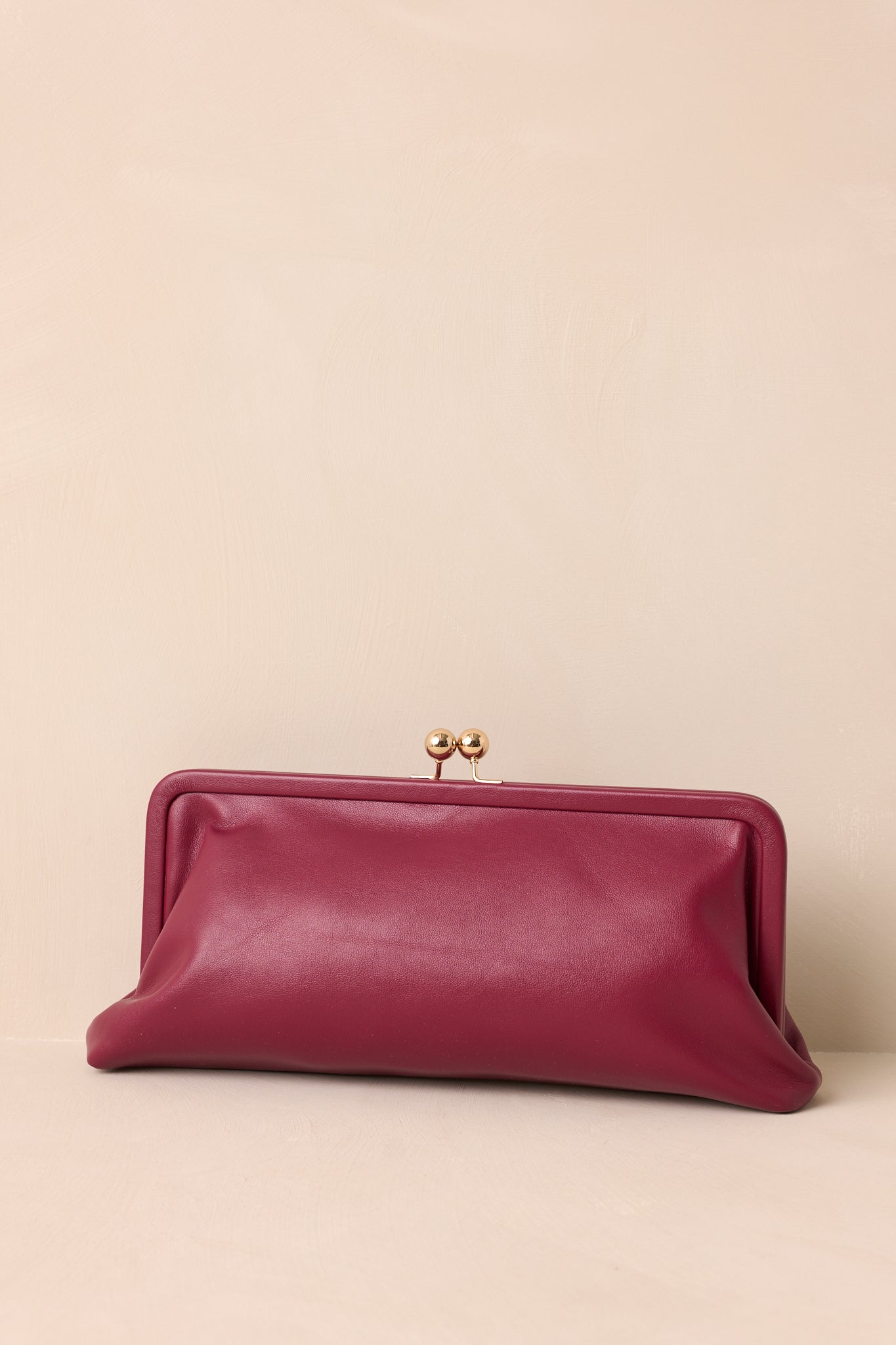 Full-length front view highlighting the smooth burgundy faux leather and overall compact design of the clutch.