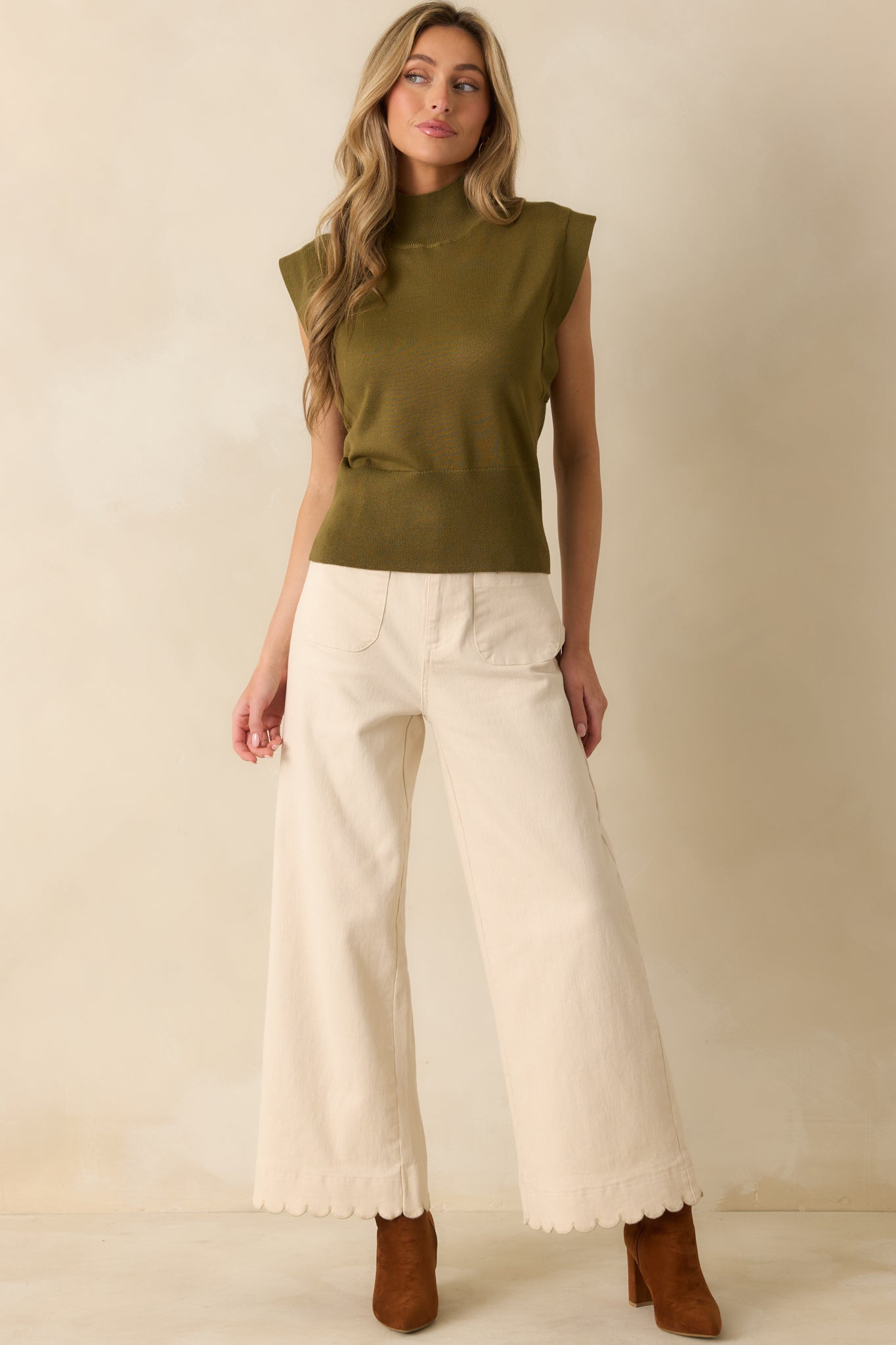 Full-length front view of fitted knit top with mock neckline and structured waistband.