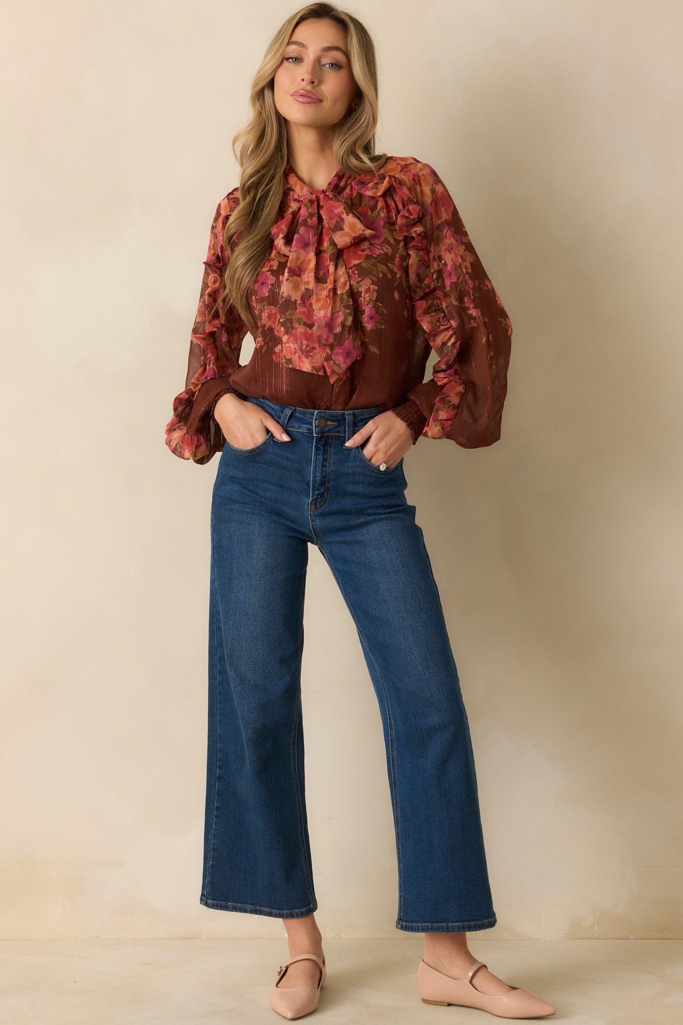 Full-length front view of flowy brown blouse with multi floral pattern, ruffled front, and blouson sleeves.