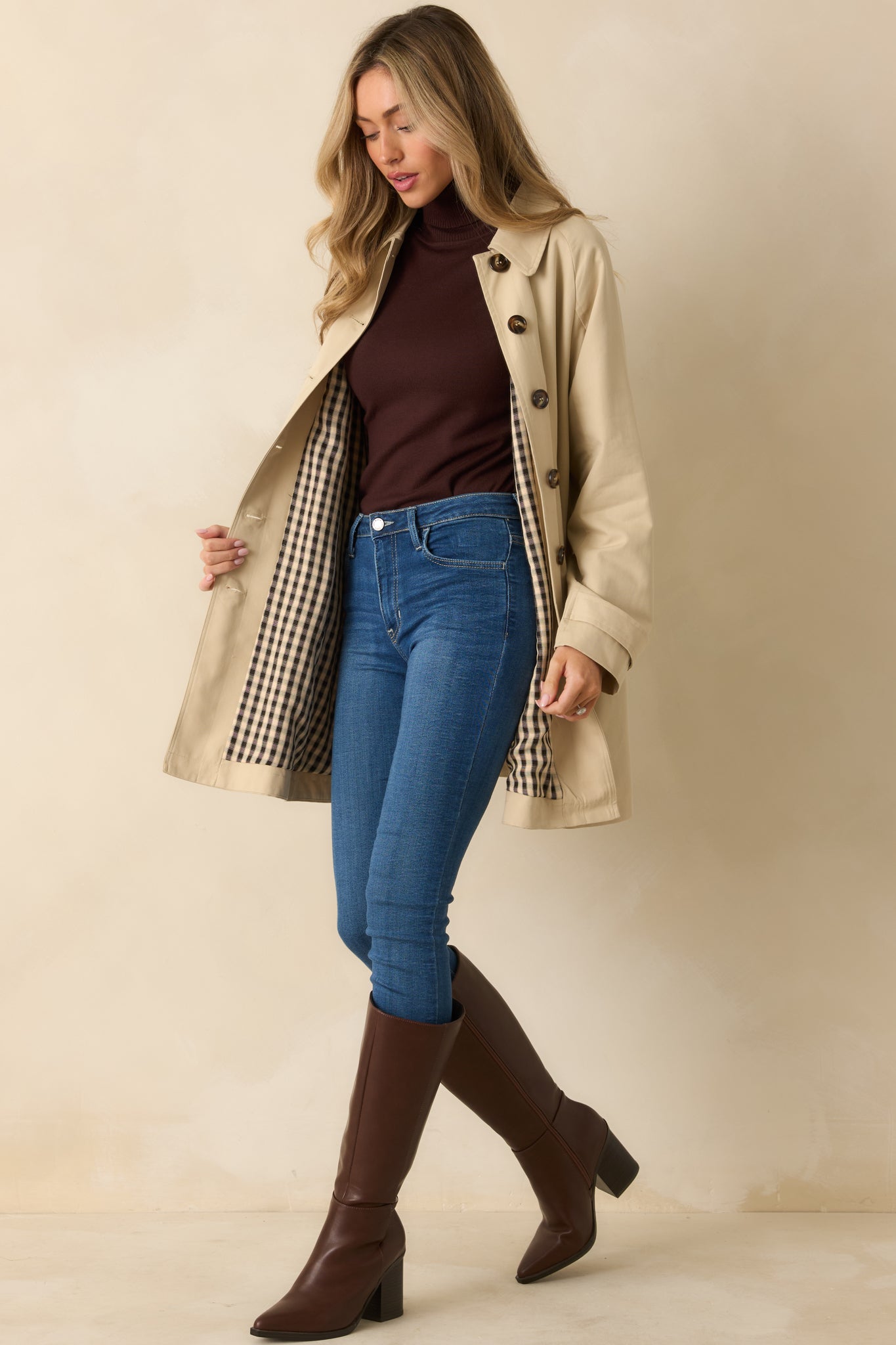 Full-length view of beige trench coat showing structured design and classic timeless finish.