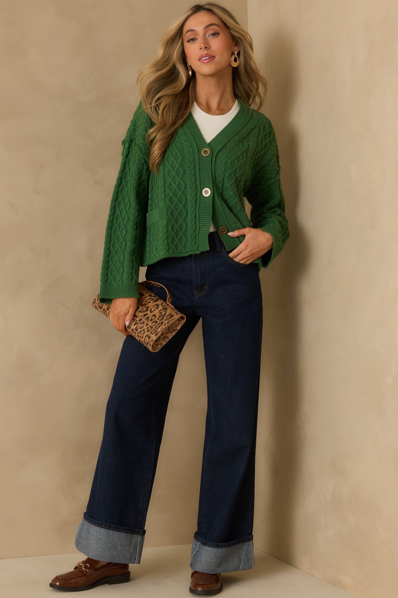 Full length view displaying the cardigan’s ribbed hems, cable knit detailing, and deep green color throughout.
