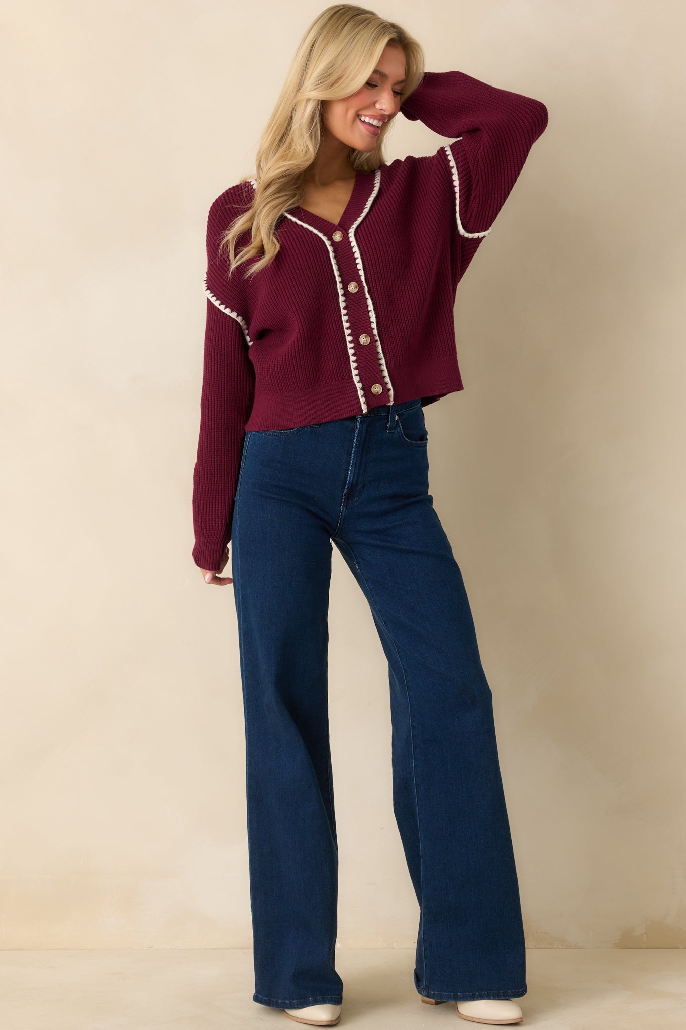 The full silhouette shows the long sleeves, relaxed fit, and contrasting white whipstitch details framing the front and cuffs.