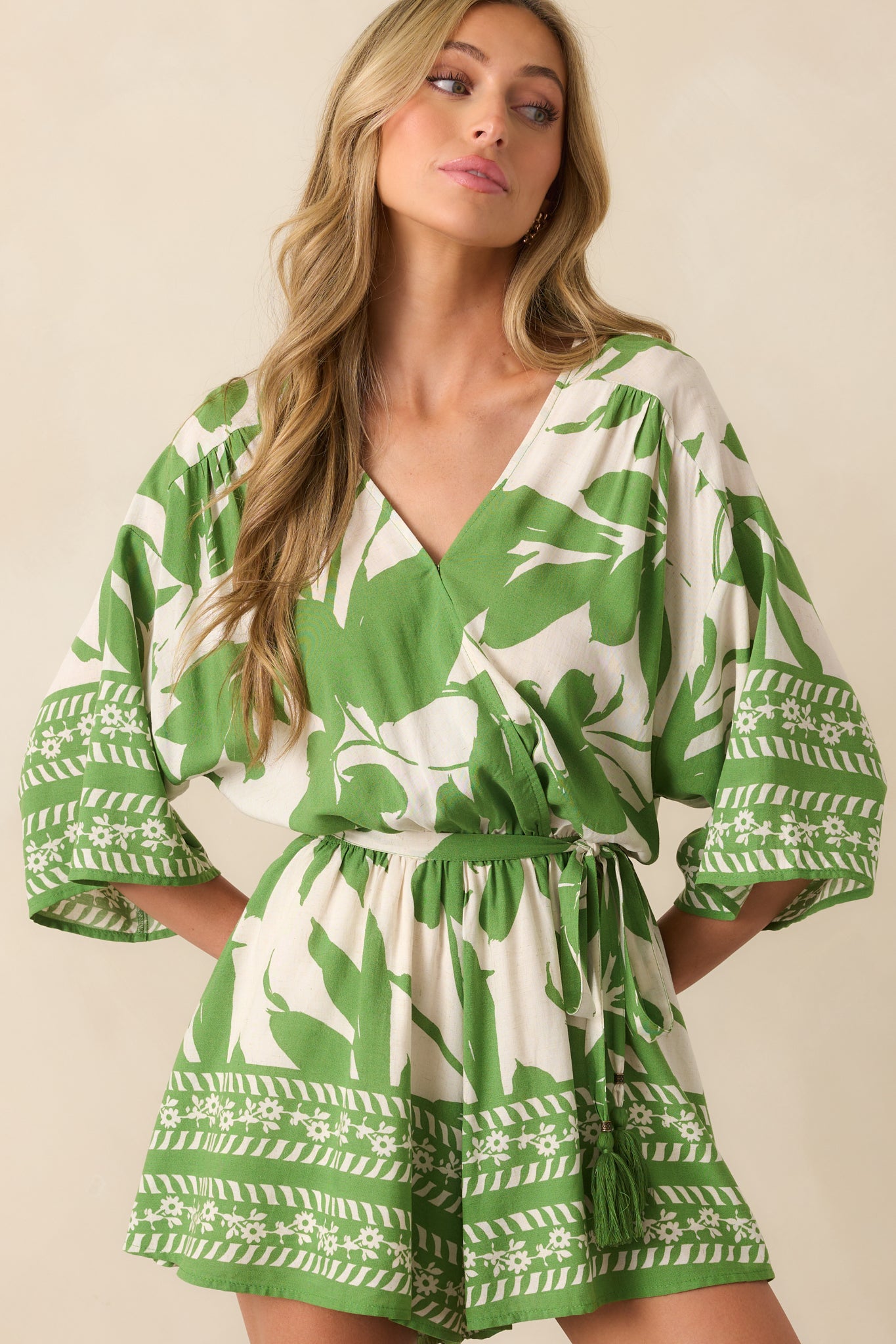 Full-length view of an ivory romper with an allover green floral print and oversized short sleeves.