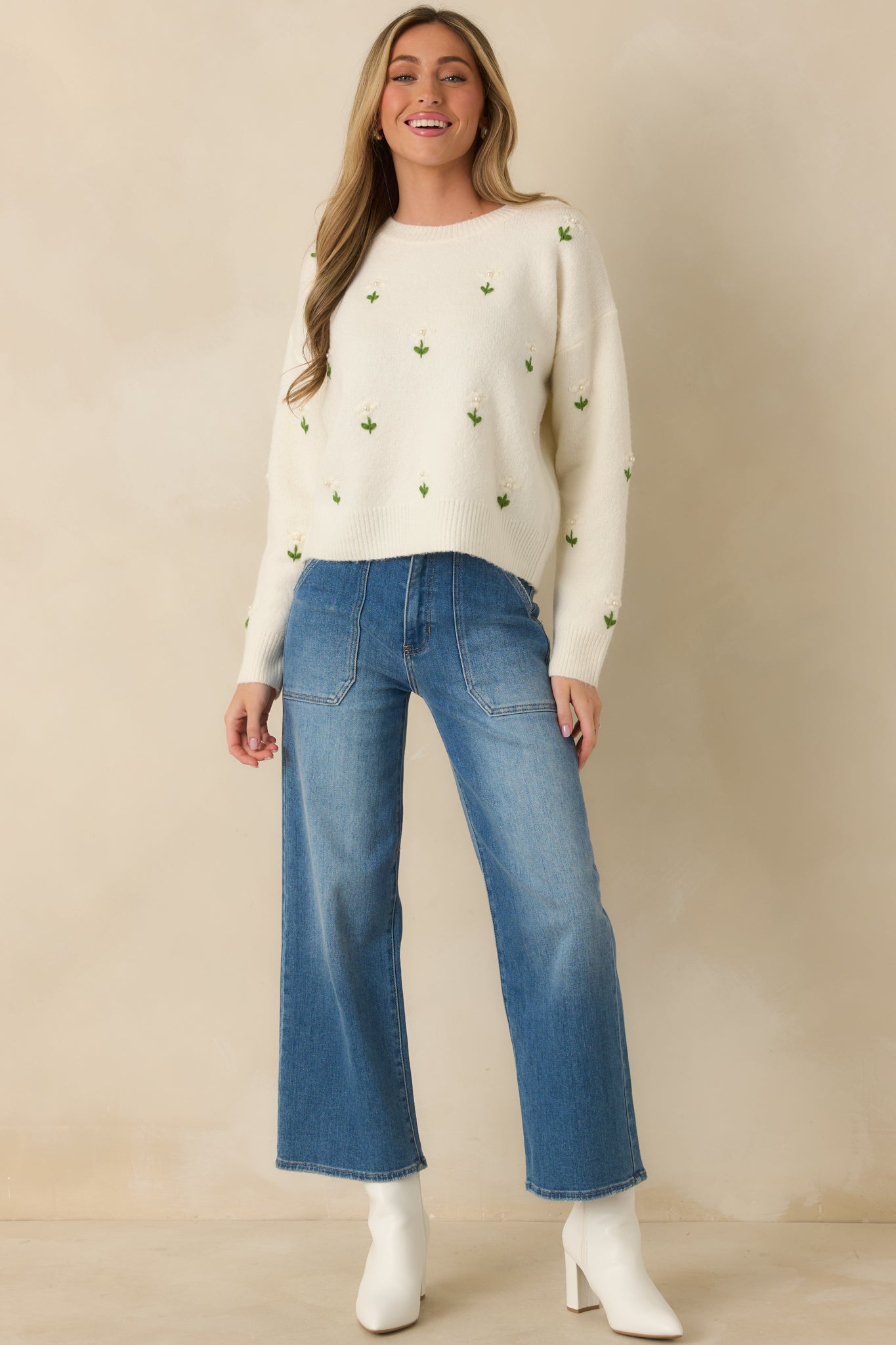 Full-length front view of the ivory sweater showcasing the sewn-on floral appliqués and relaxed silhouette.