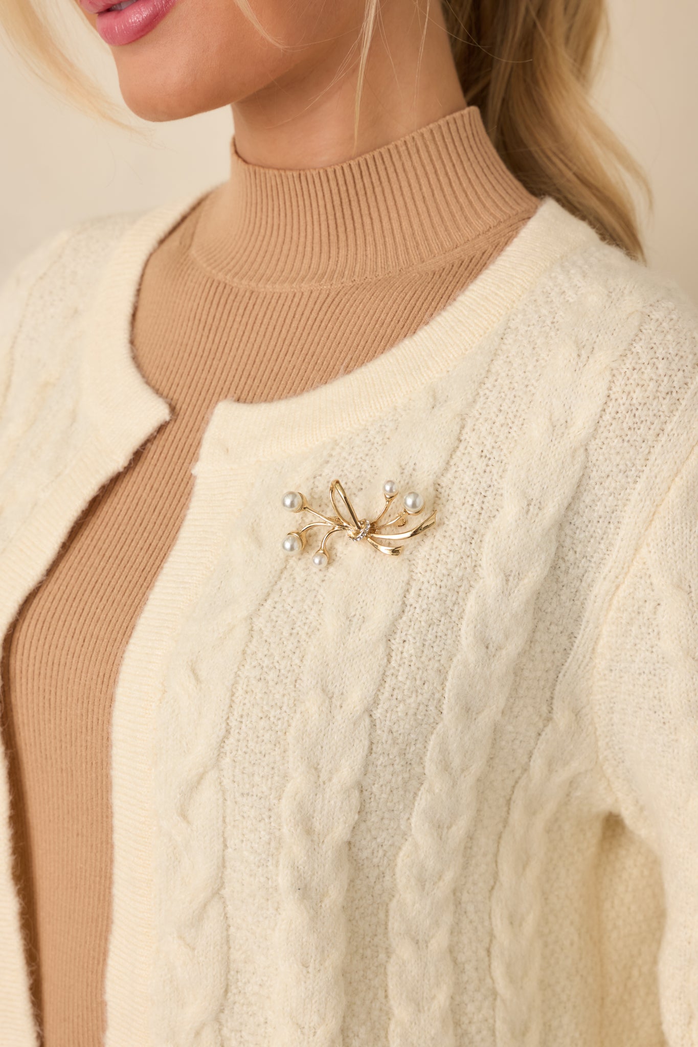 Full view of the pearl and gold brooch featuring a delicate bow-inspired design with faux pearl accents.