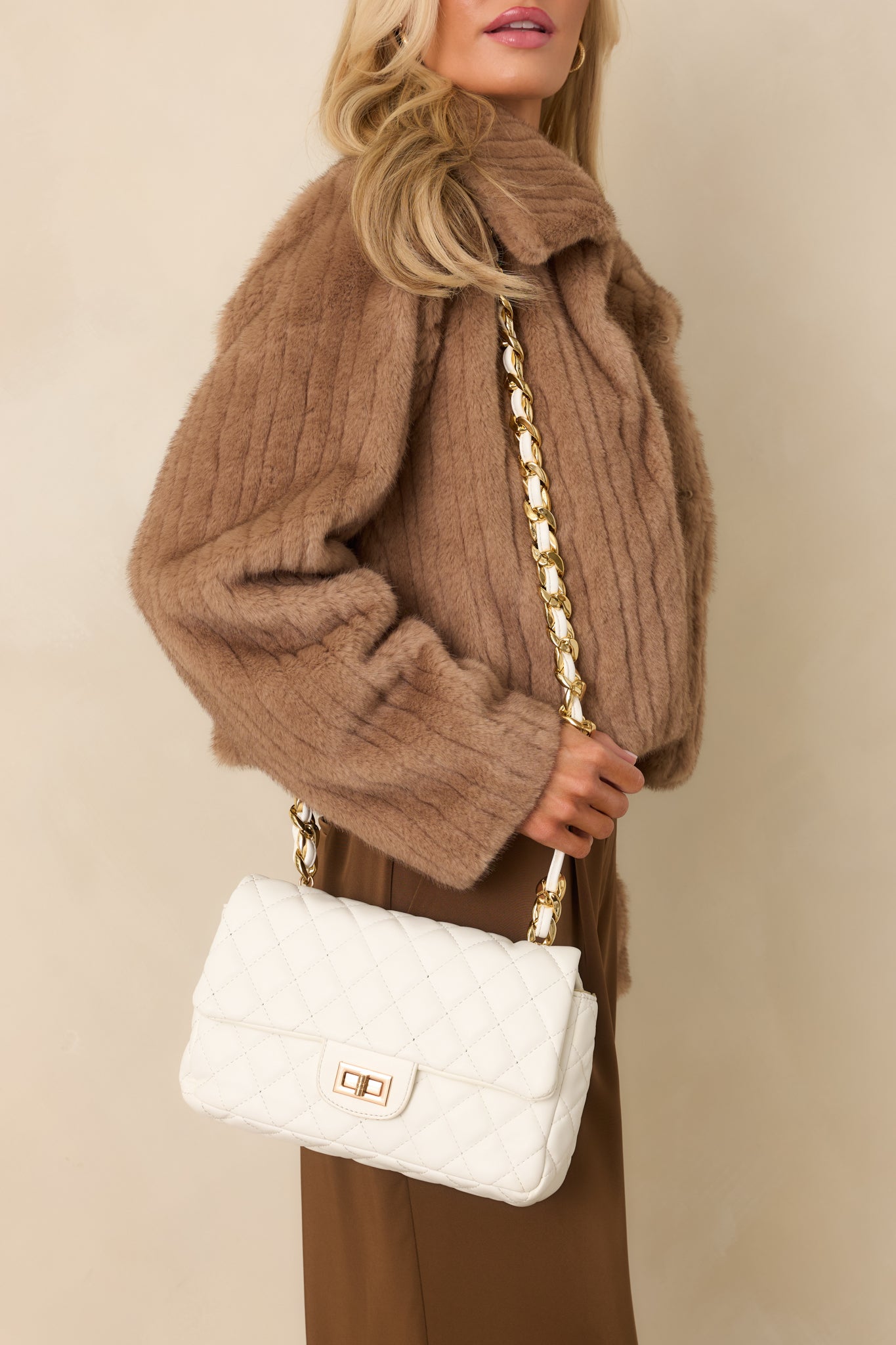 Angled full view of the white bag highlighting the chain strap and compact structured shape.