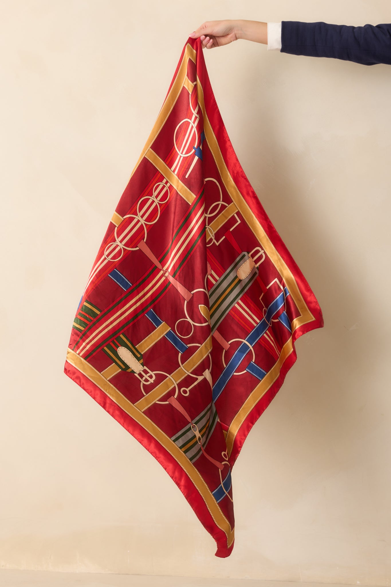 The red satin scarf shown in full, highlighting its smooth finish and multicolored print across the fabric.