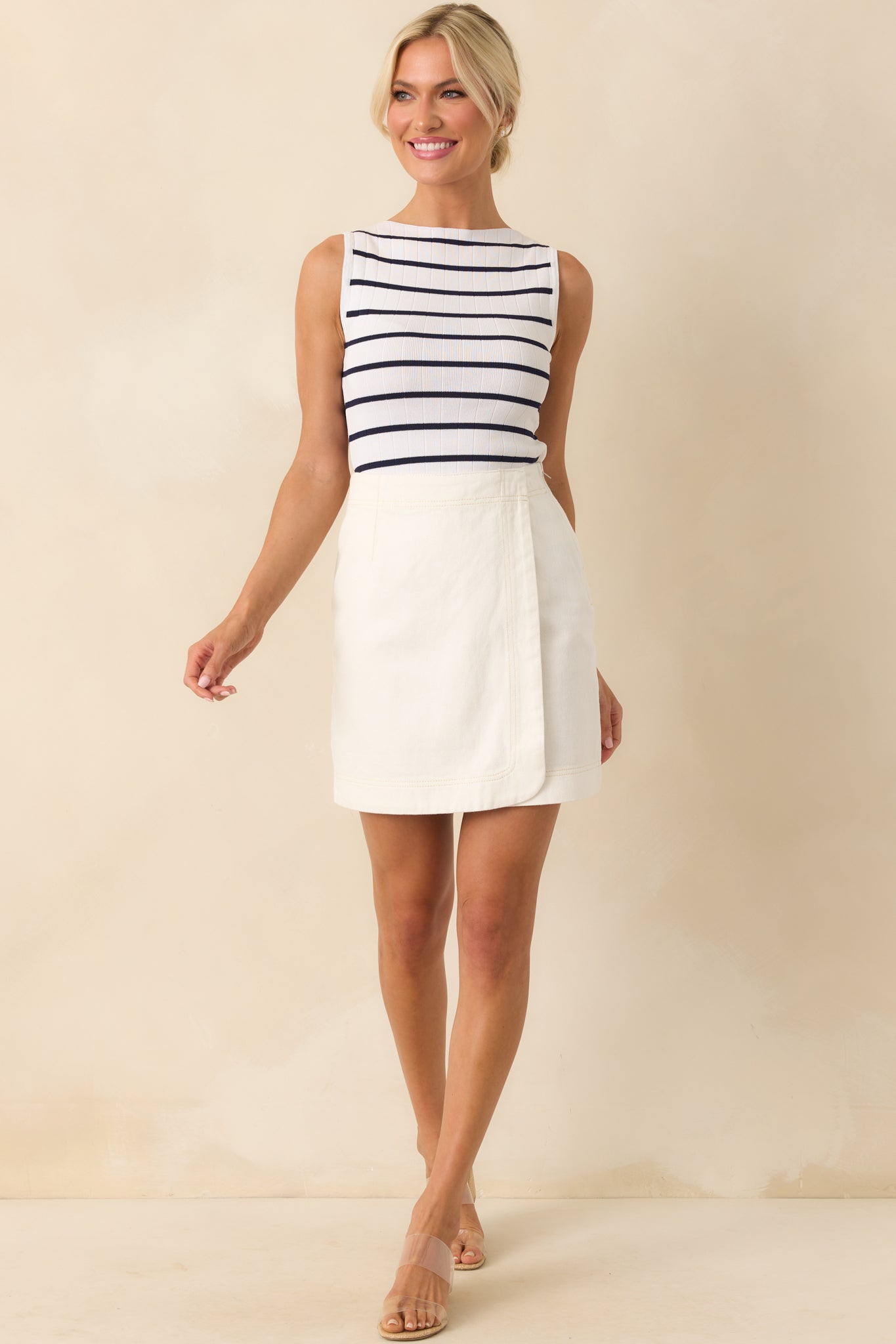 A full body front view showing the white cotton denim skirt with its high rise waist and wrap front panel design. 