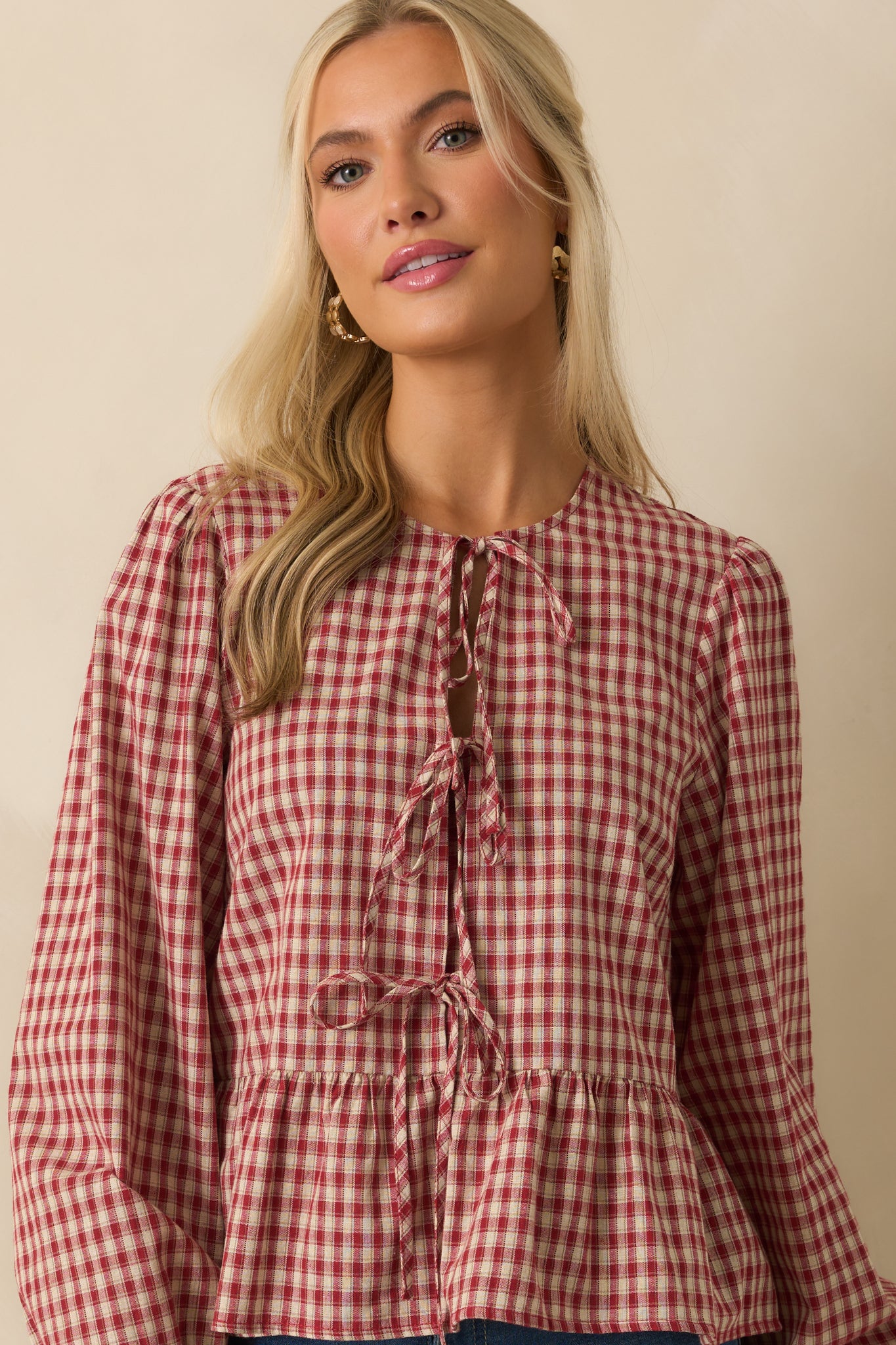 Cropped front shot of gingham blouse highlighting self-tie bow closure and round neckline.