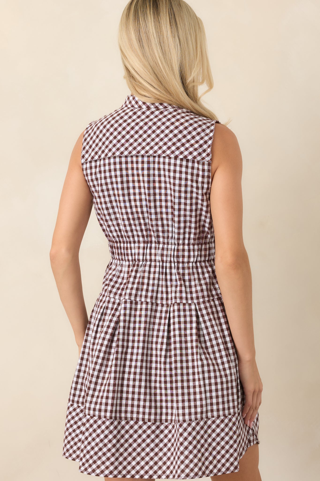 Rear view of the gingham mini dress showcasing its relaxed silhouette, short sleeves, elasticized waist, and flowing skirt.