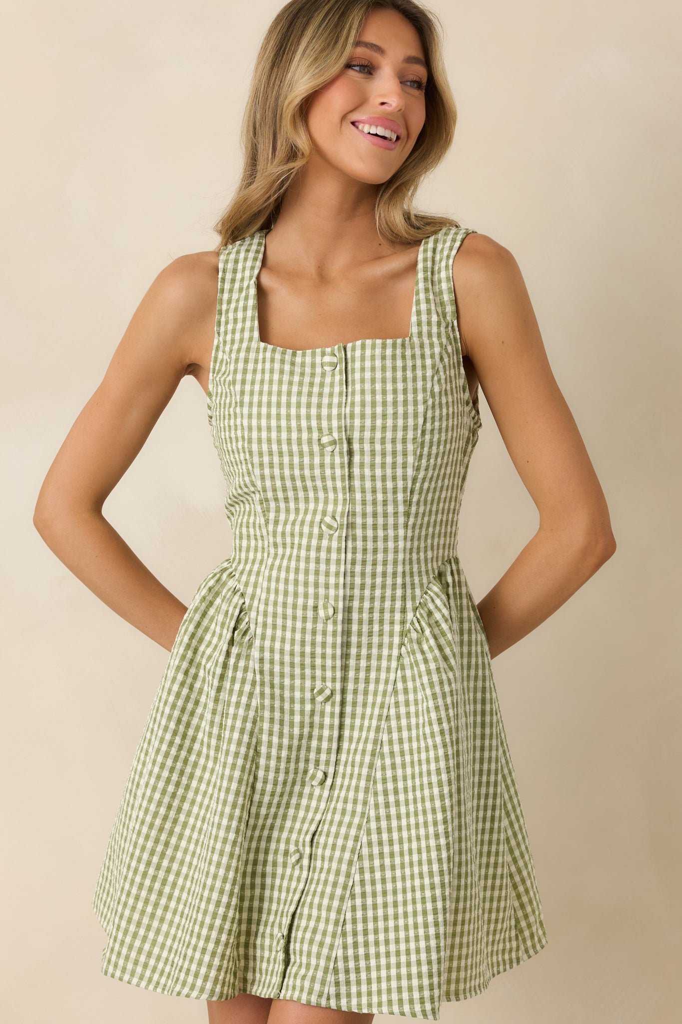 Close view of gingham mini dress showing sleeveless design and tailored waist shaping.