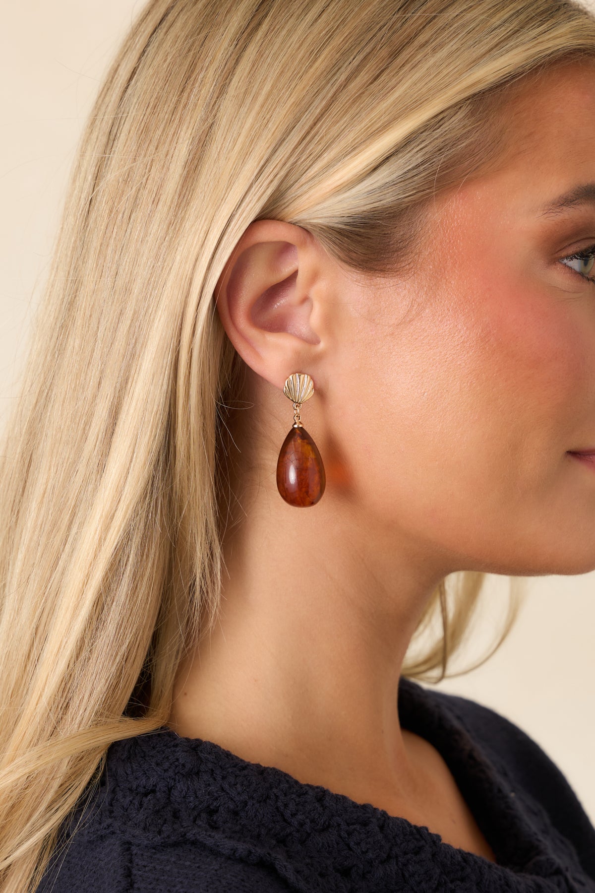 Glossy amber-brown drops hang beneath ridged gold-tone shell-shaped studs.