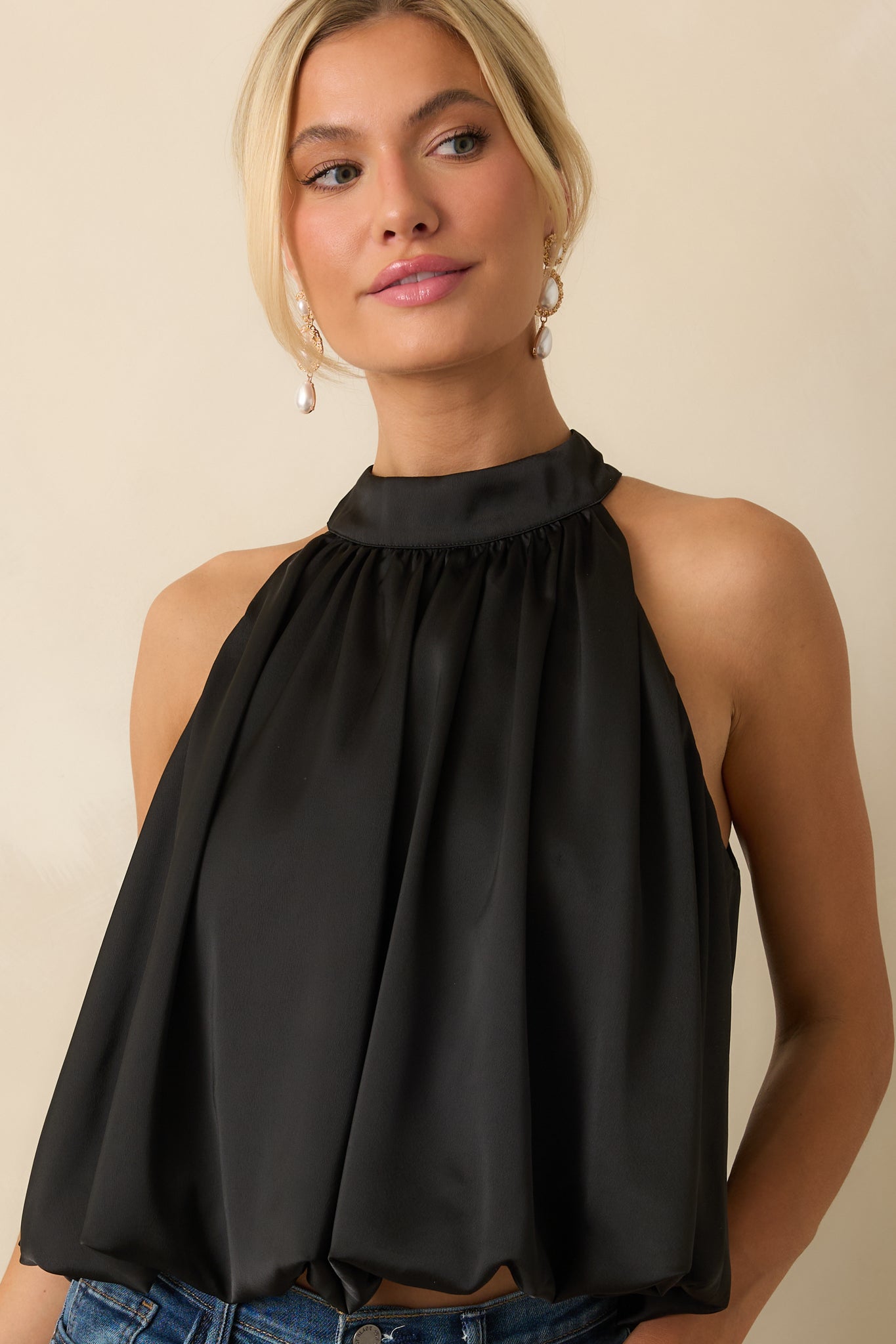 Detail view of the glossy satin fabric showing the gentle blouson silhouette and subtle sheen.