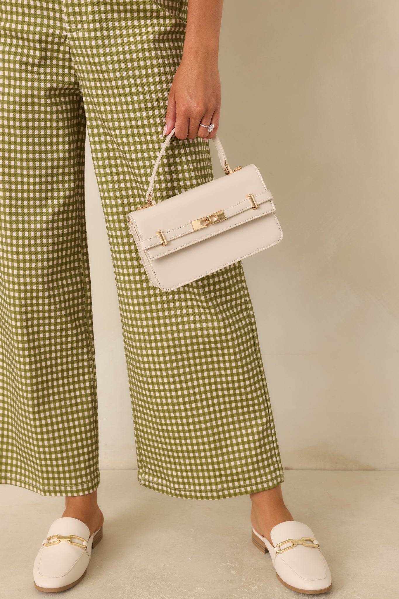 Elegant faux leather handbag showcasing polished gold-tone accents, interlocking front detail, detachable strap, and refined shape.