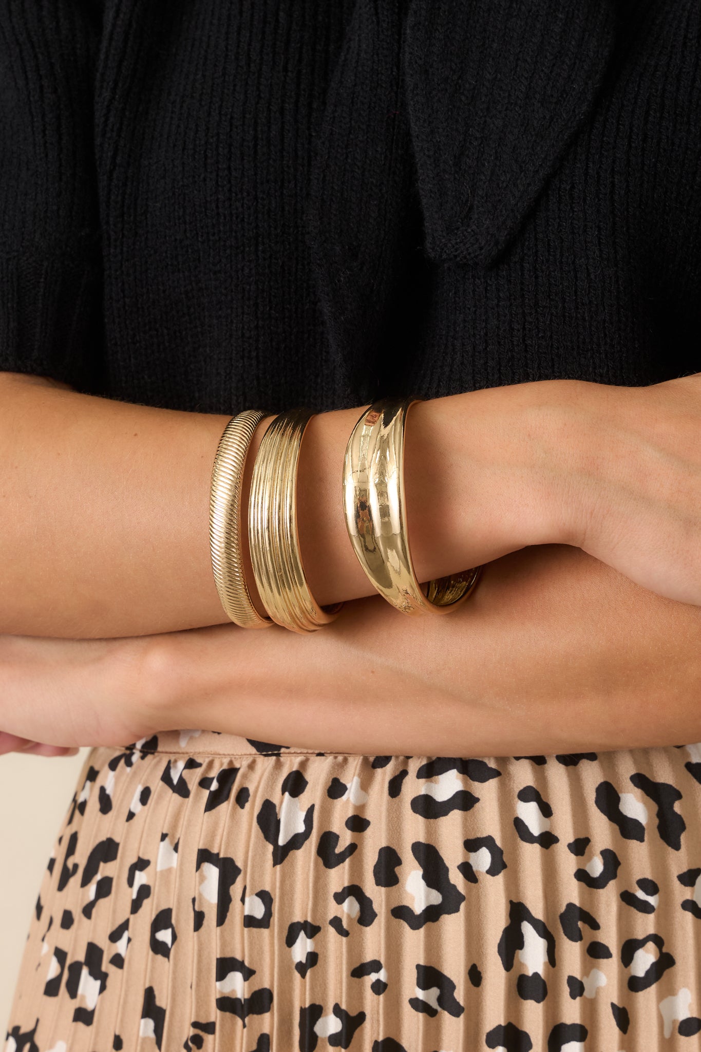 Layered gold-tone bracelets showcasing a wide polished bangle, herringbone-inspired texture, and dimensional ridged design