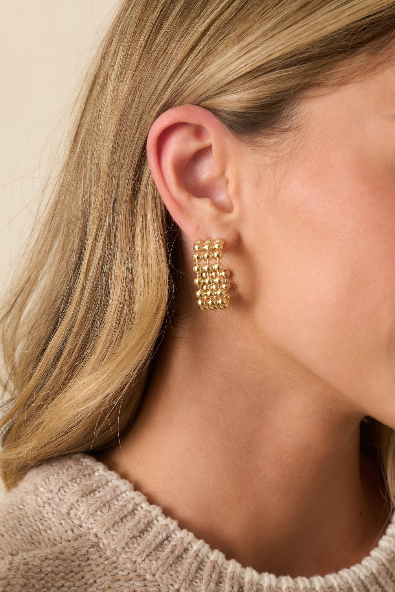 A cropped front view showing the open hoop silhouette with stacked rows of rounded gold beads in a grid-like pattern.
