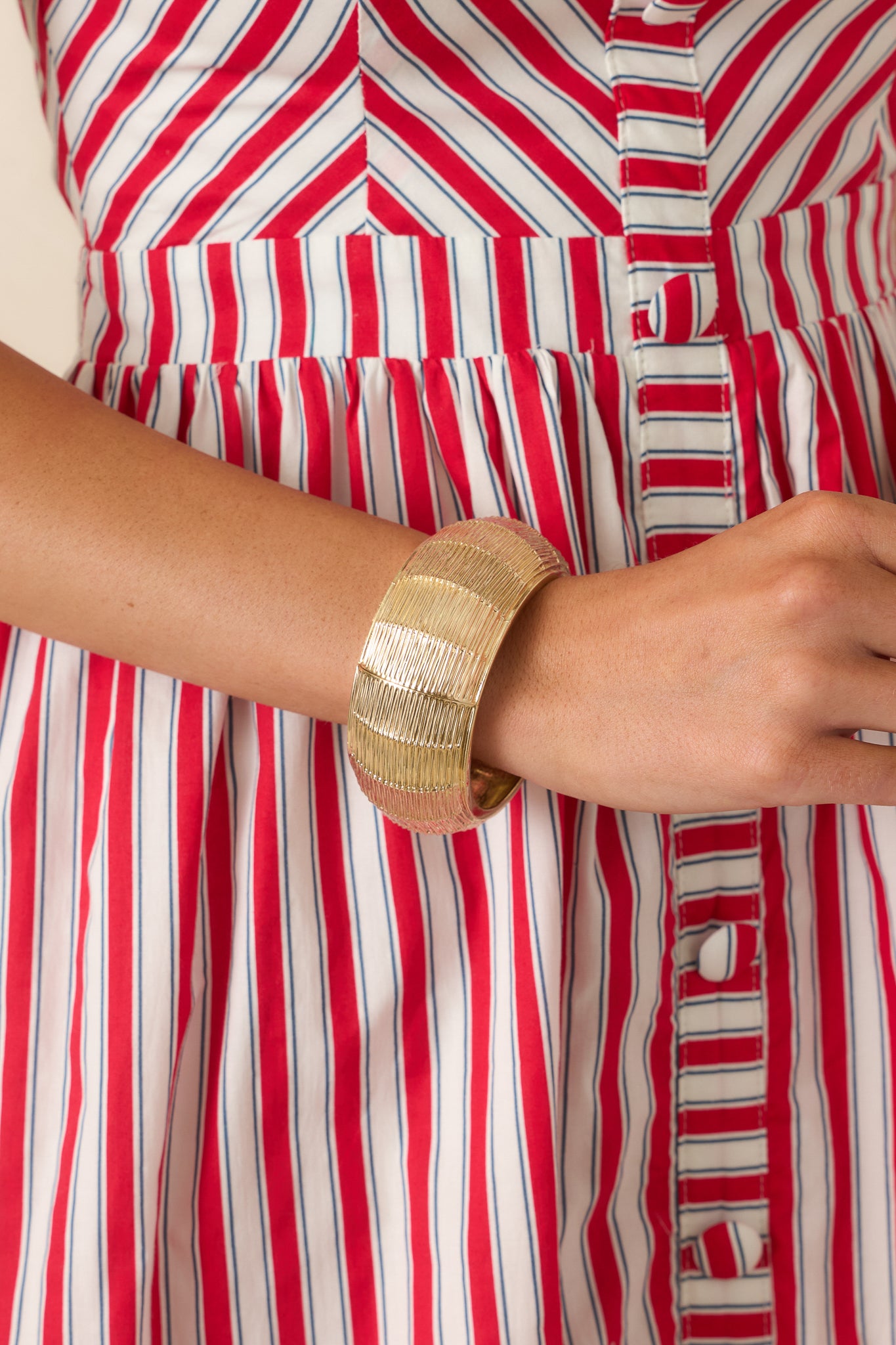 Gold bracelet featuring a textured design, polished hardware accents, and a hinged closure for a statement look.