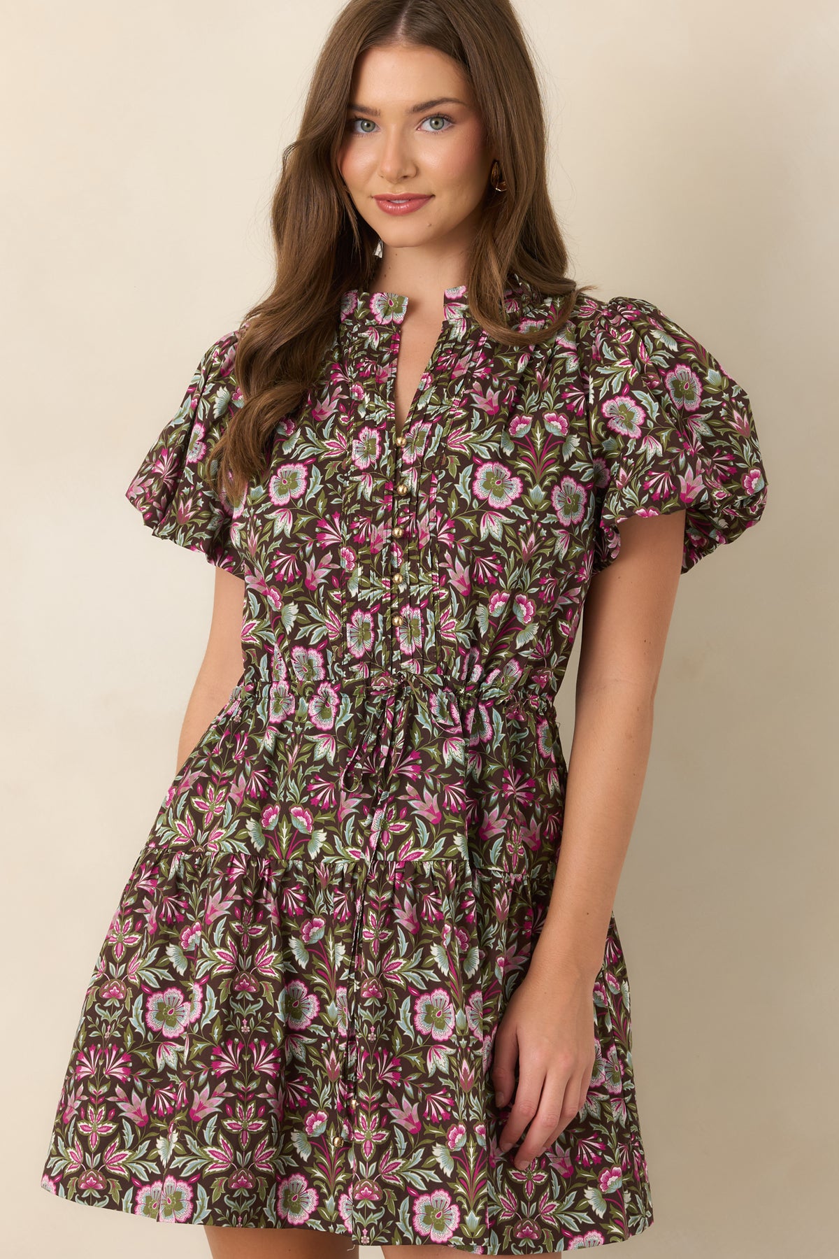 Gold-tone buttons accent the pleated front while flutter sleeves add delicate movement to the floral design.
