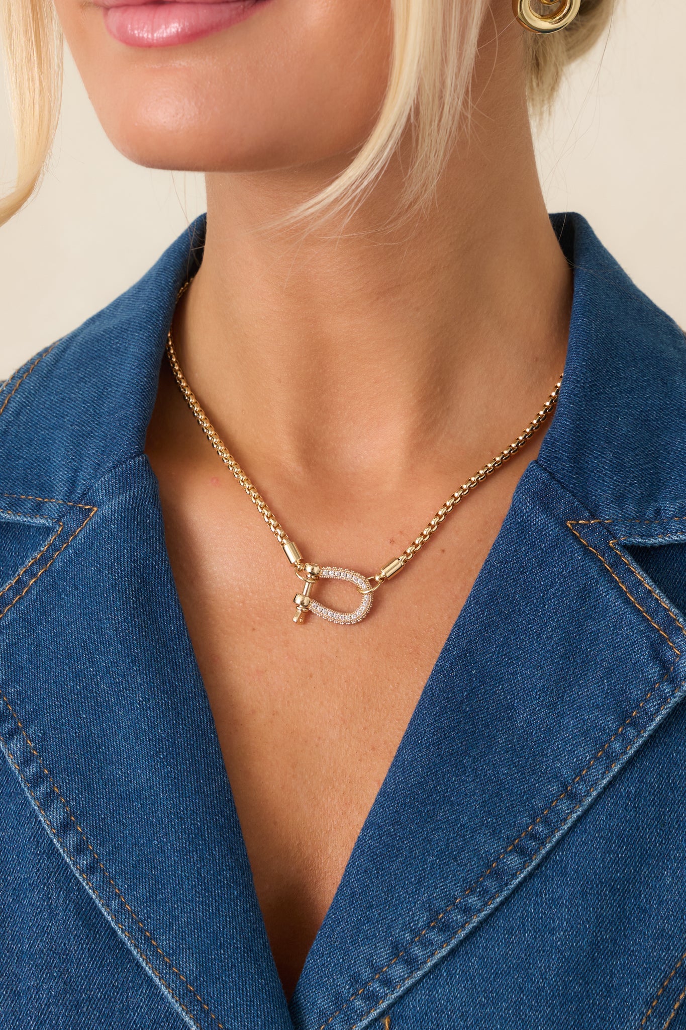 Refined necklace showcasing a polished gold-tone box chain and shimmering crystal pavé shackle clasp.
