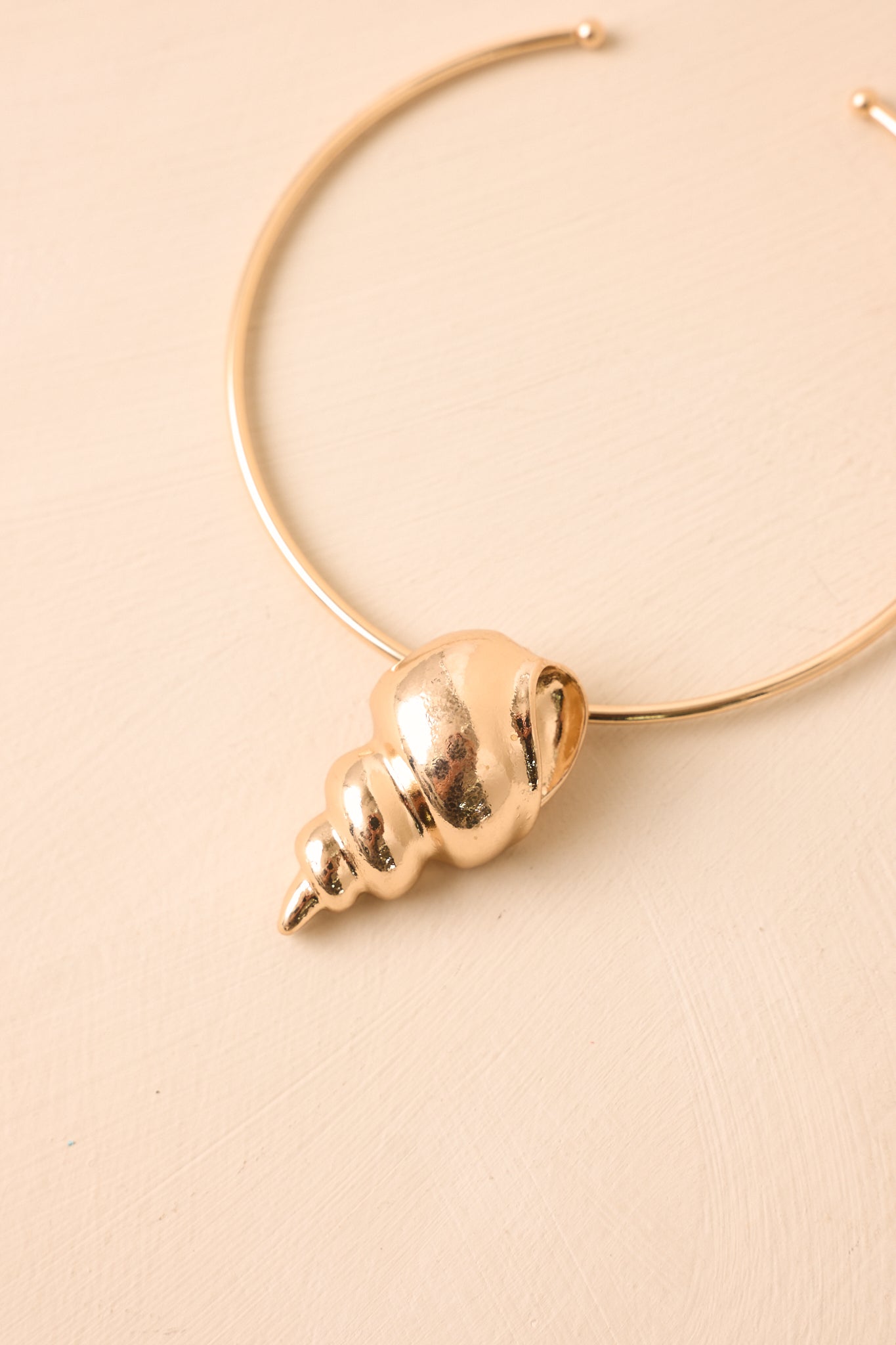Close-in crop highlighting polished metal curve and dimensional shell charm detail.