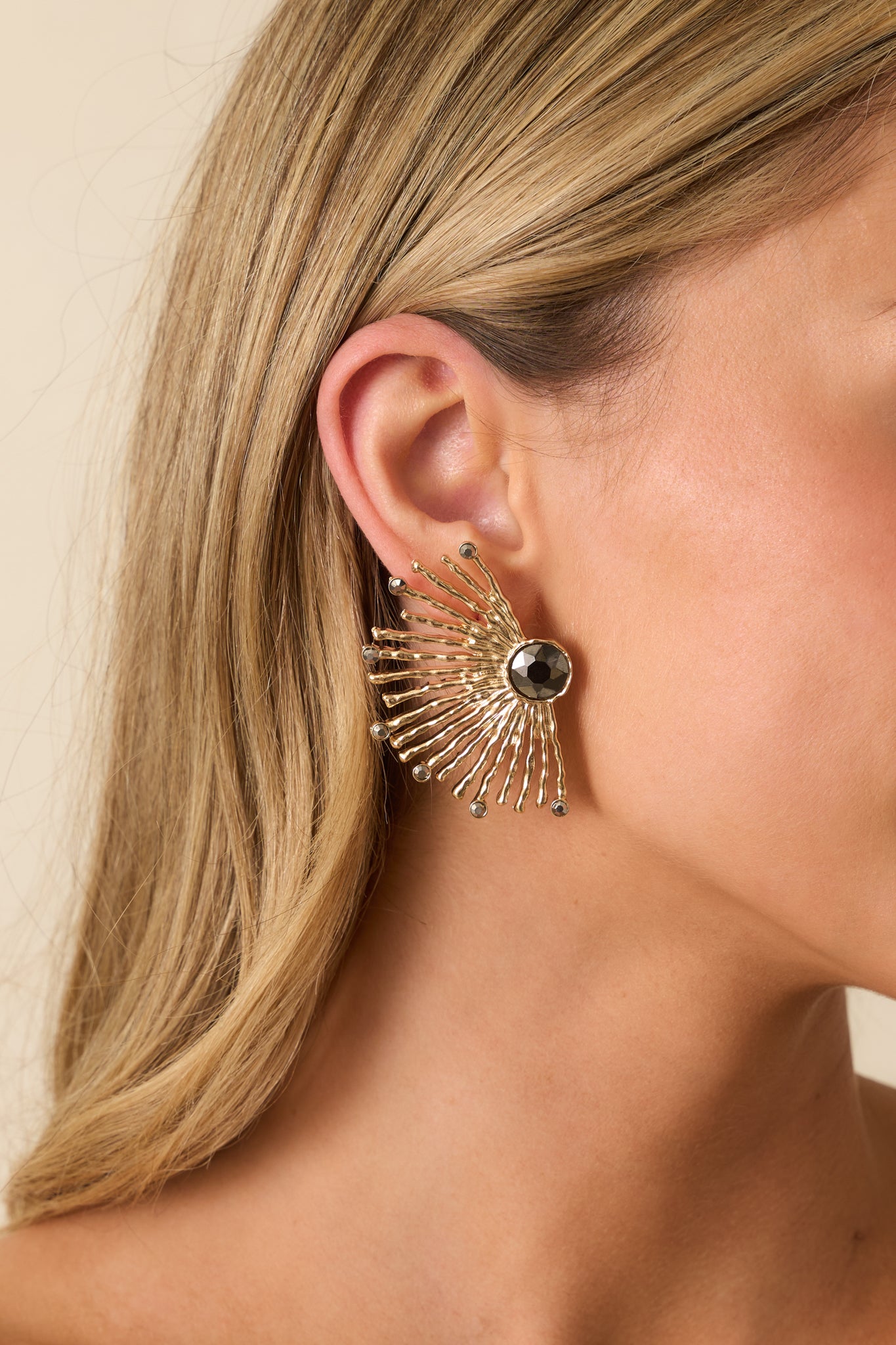 Gold fanburst earrings featuring a faceted black center stone and radiating gold spokes with rounded tips shown from the front.