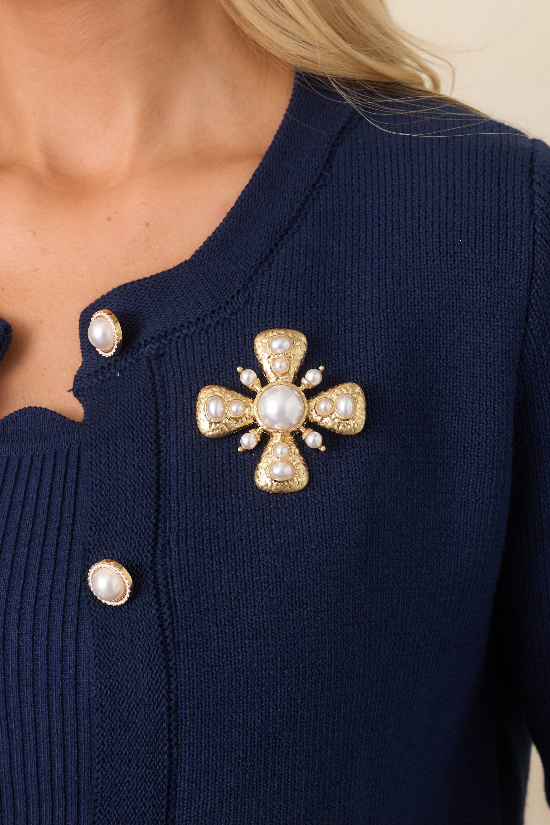 Gold brooch featuring a large faux pearl center, four triangular sections with pearl accents, and four smaller arms with pearl details.