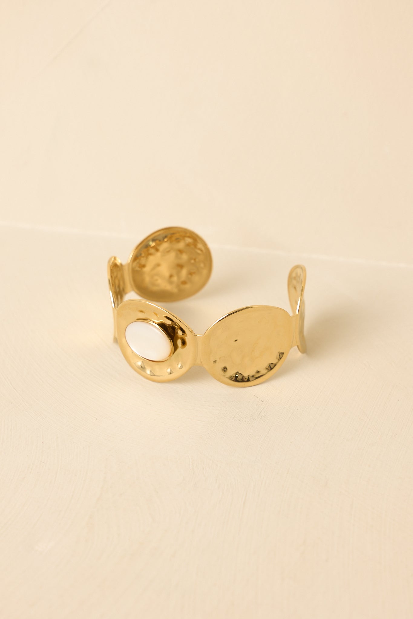 Close-up of gold hammered circle cuff emphasizing textured finish, smooth central accent, and open slip-on design.