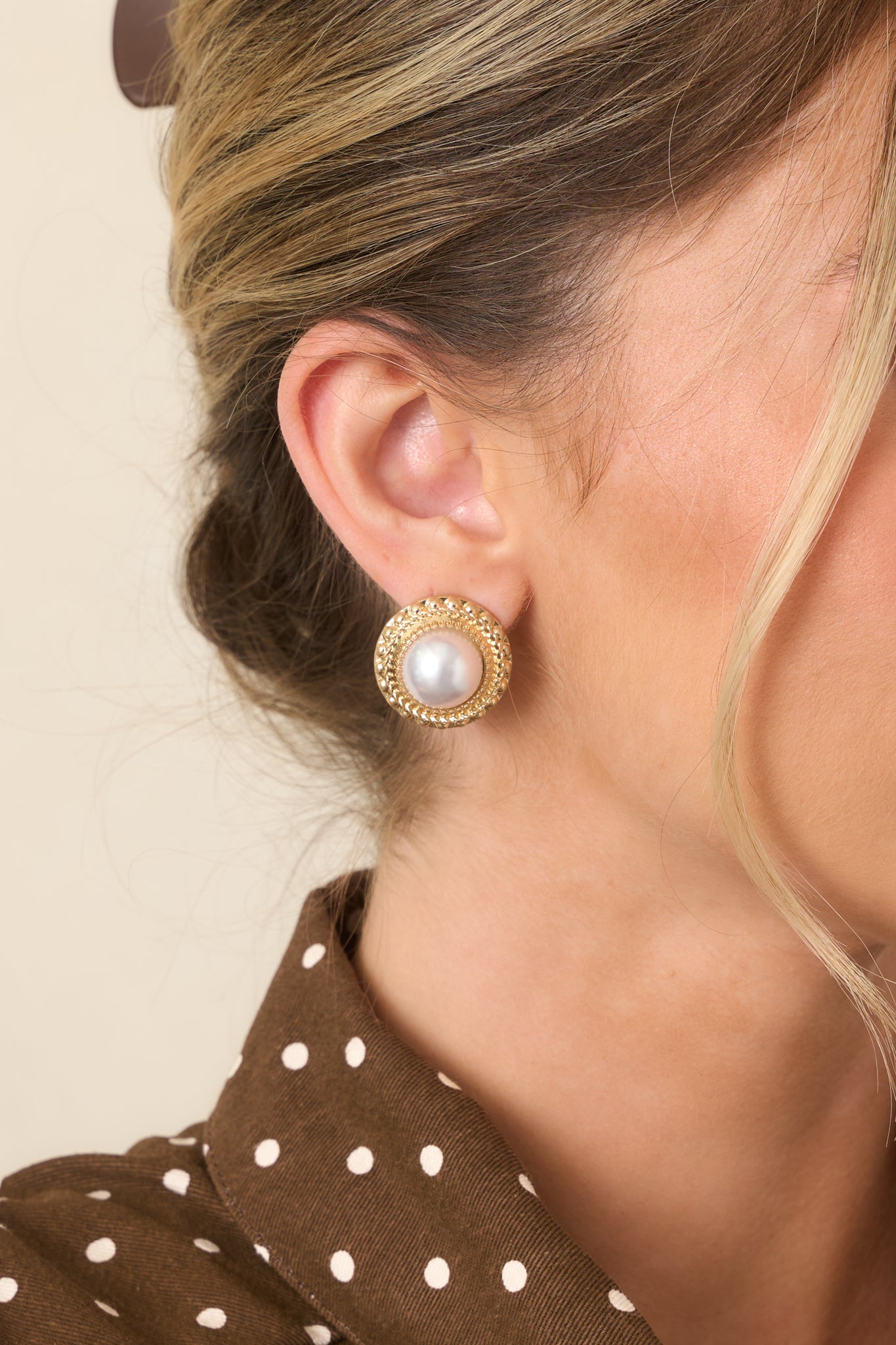 Gold and ivory stud earrings with large circular shapes, oversized ivory pearl centers, and thick textured gold borders with braided edging.