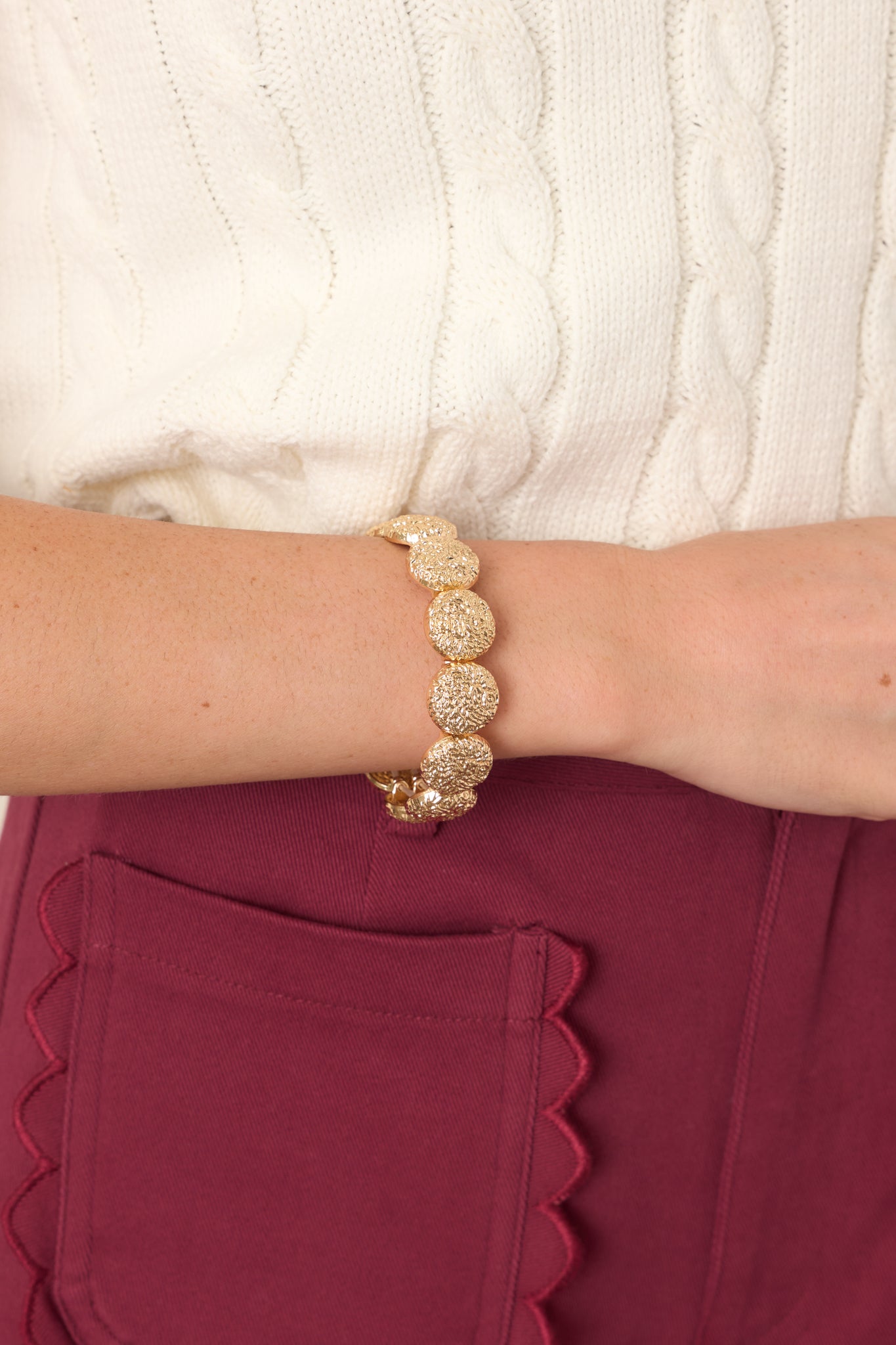 Close-up of the bracelet's textured gold-tone discs, showcasing their pebbled surfaces and dimensional sculptural finish.