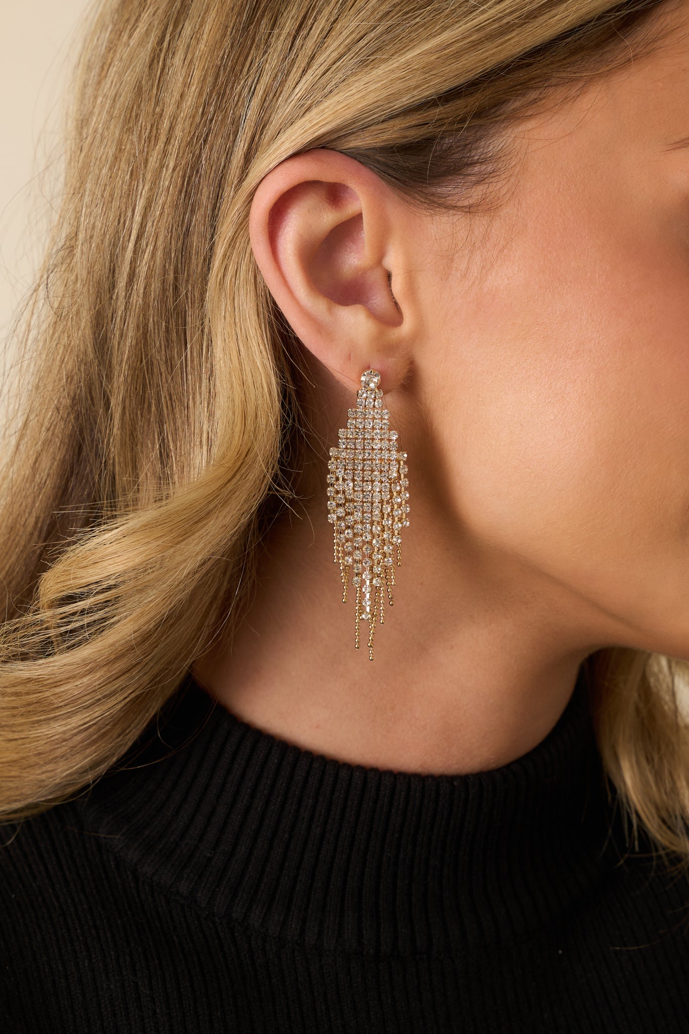 Cropped photo showing gold and rhinestone mesh diamond-shaped earrings with cascading chain fringe detail.