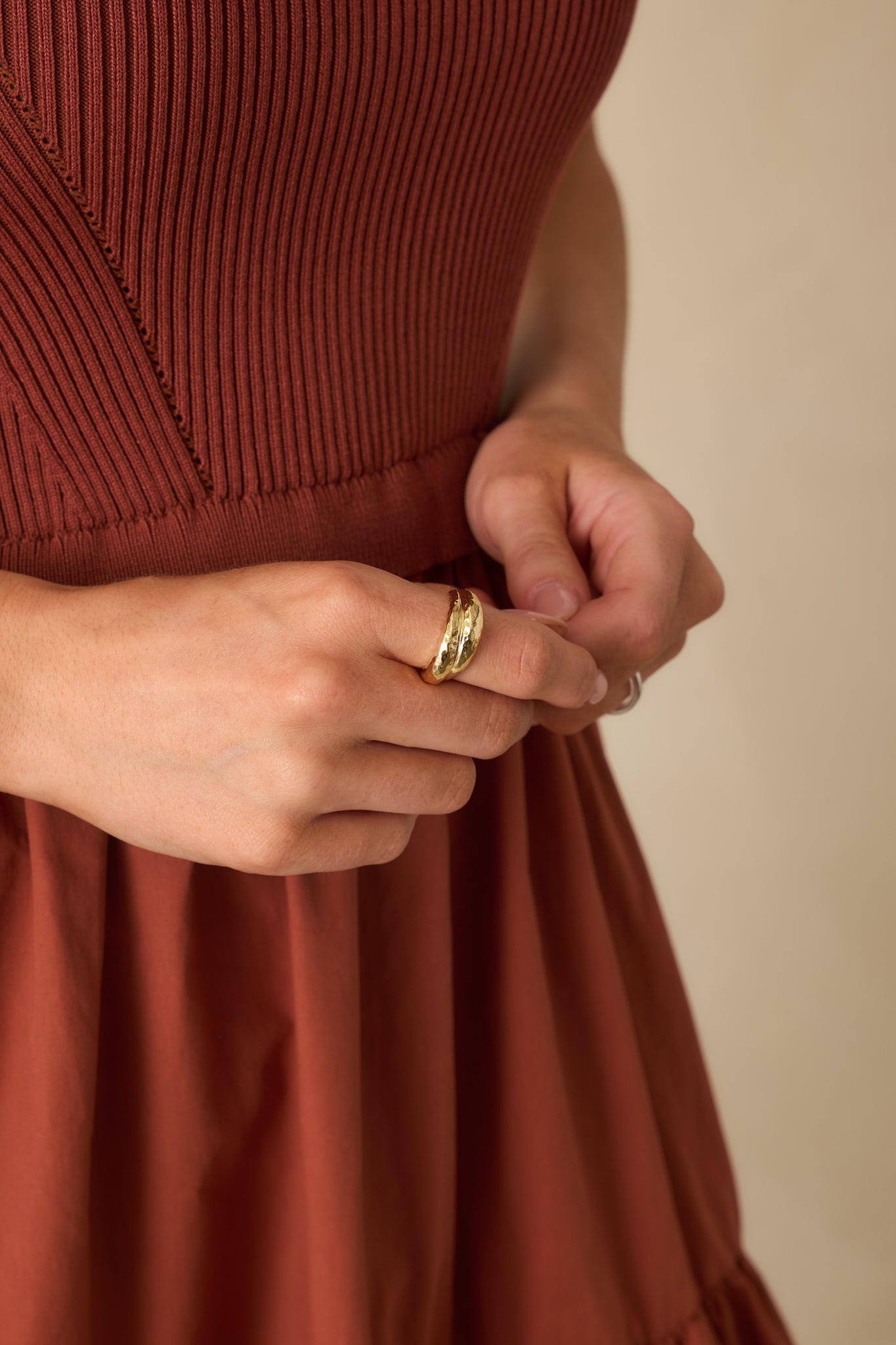 Gold ring with a wide dome shape, overlapping crossover design, and hammered texture visible from a front angle.