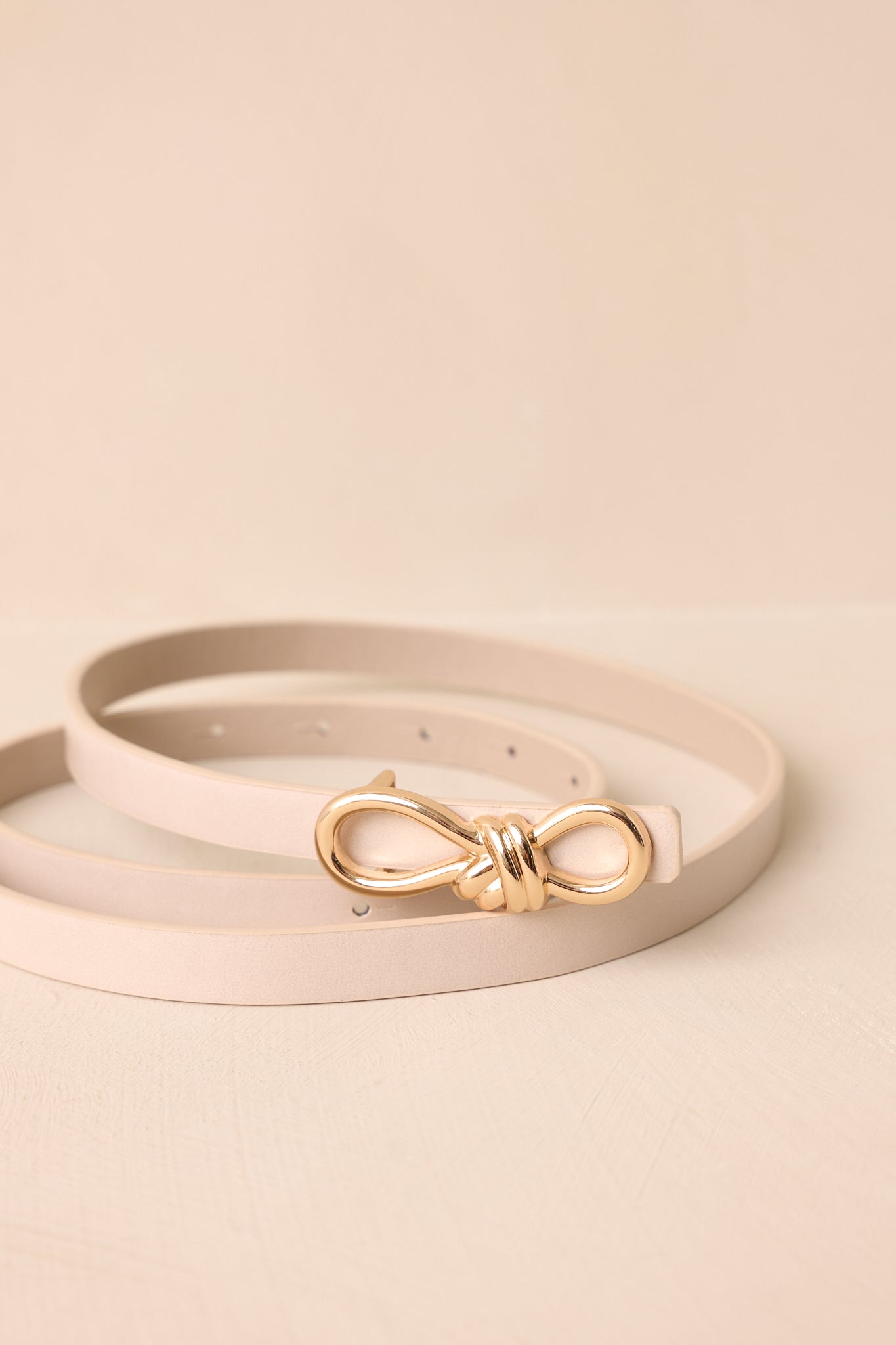 Close-up of the gold rope-inspired interlocking buckle with textured ivory faux leather strap.