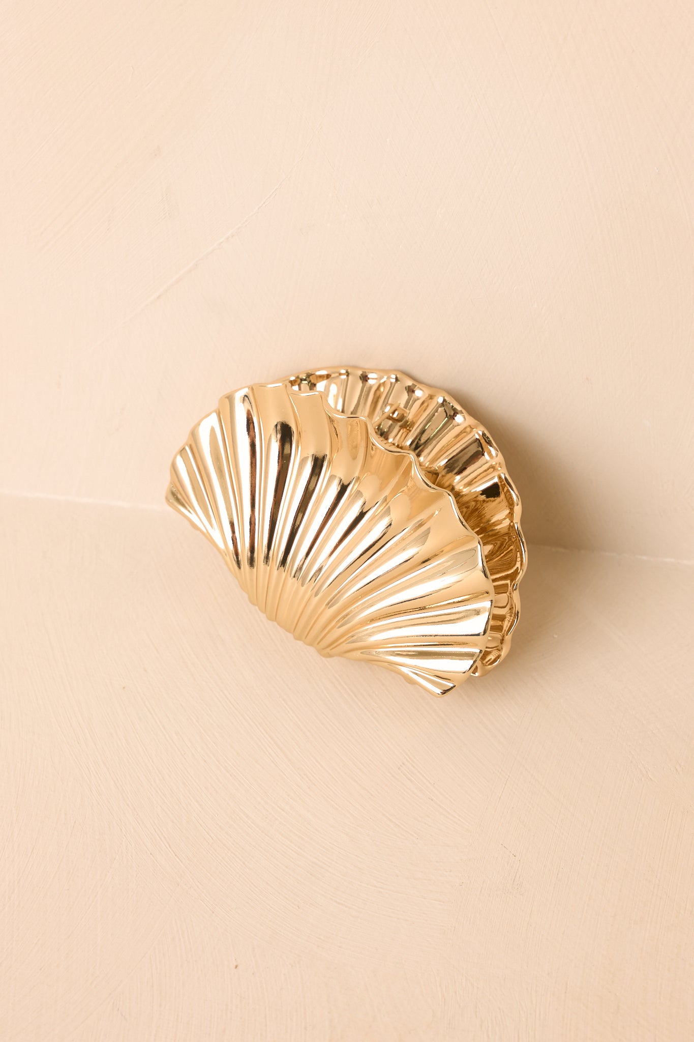 Gold claw clip featuring a smooth shell-inspired shape, reflective finish, and strong hold design.