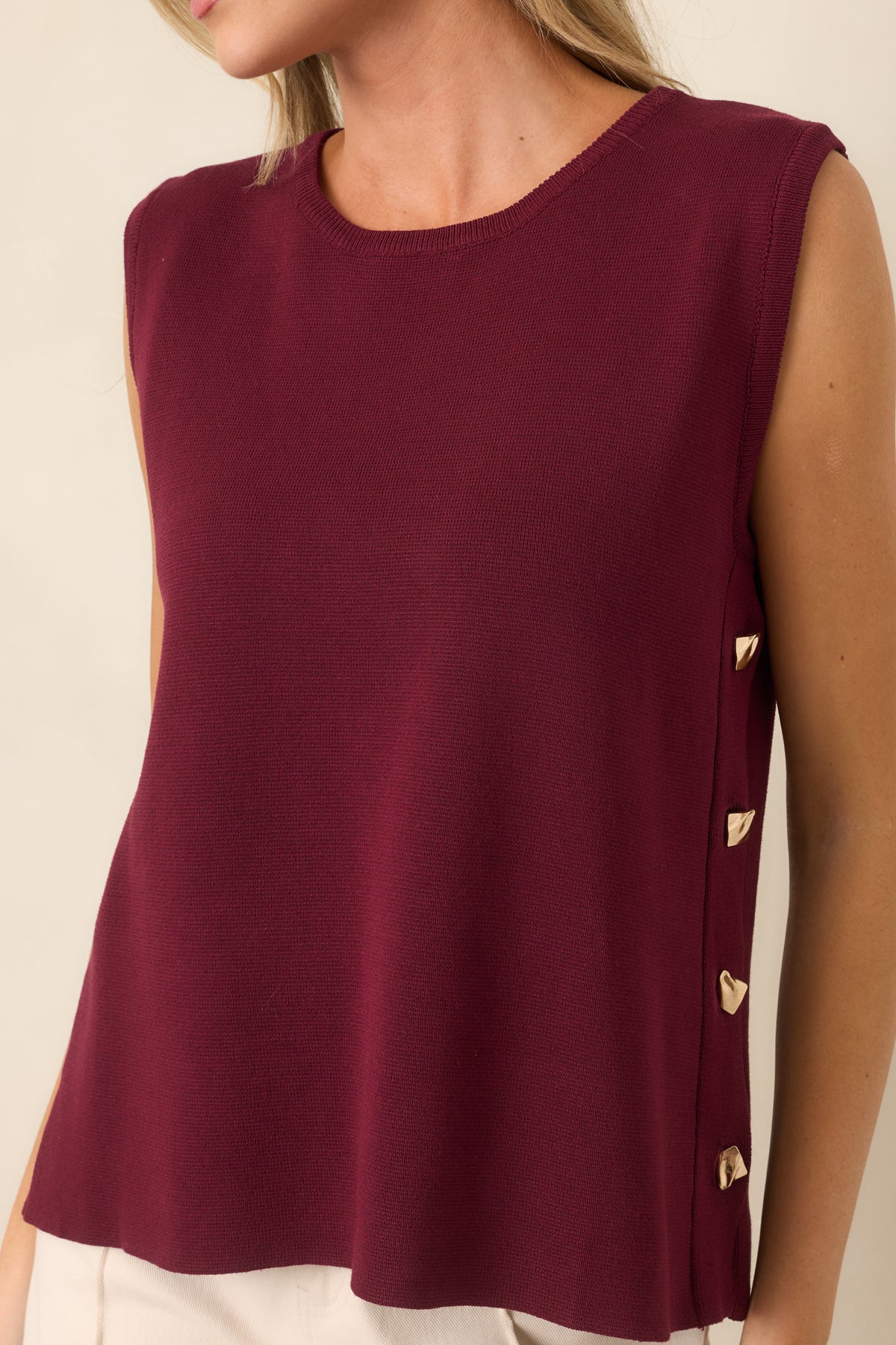 Close-up of the sweater knit top highlighting the row of functional gold-tone side buttons and smooth, softly draped fabric.