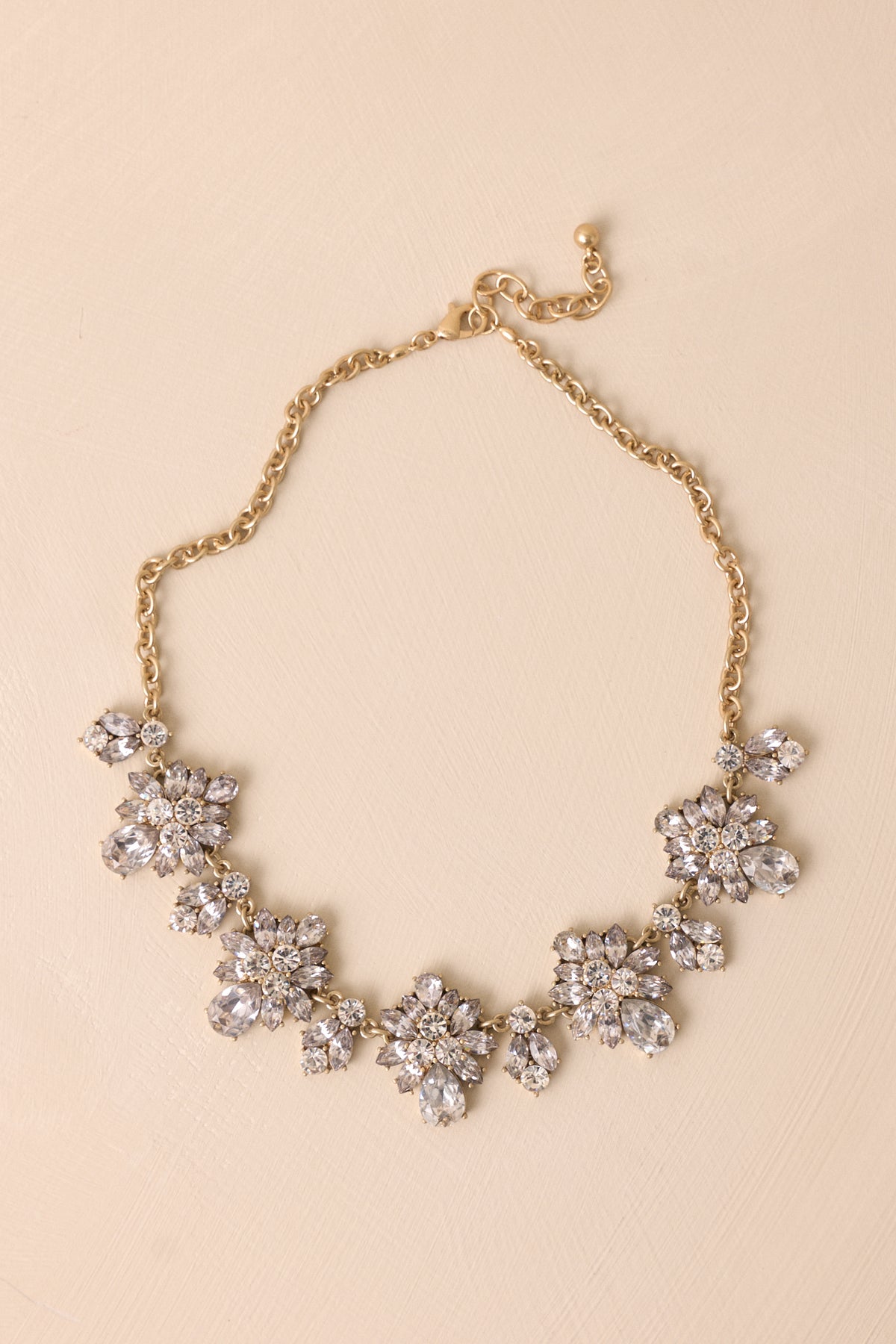 Gold statement necklace featuring a substantial chain and sparkling rhinestone pendants.
