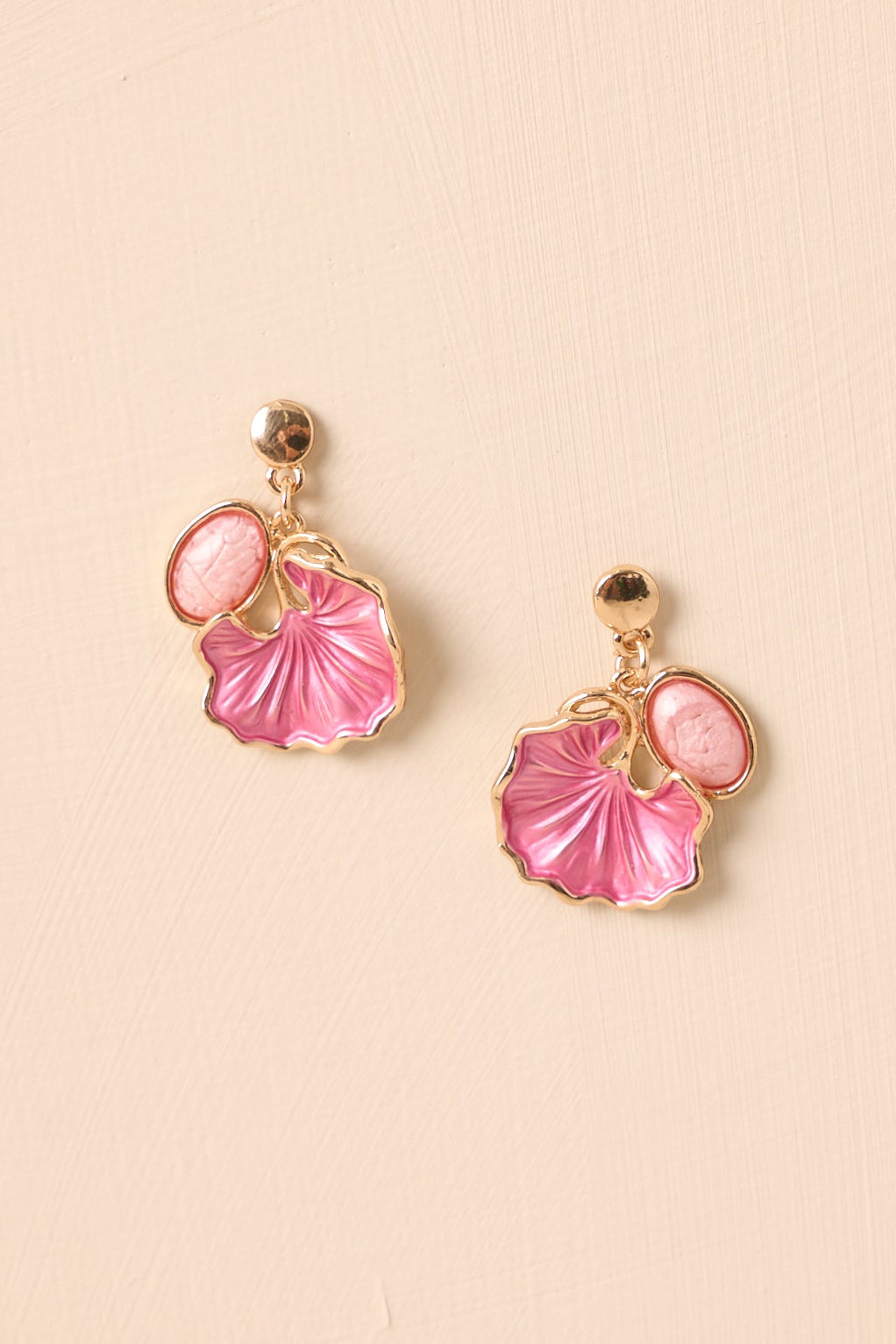 Up close of gold stud earrings with pink oval cabochon and floral petal drop.