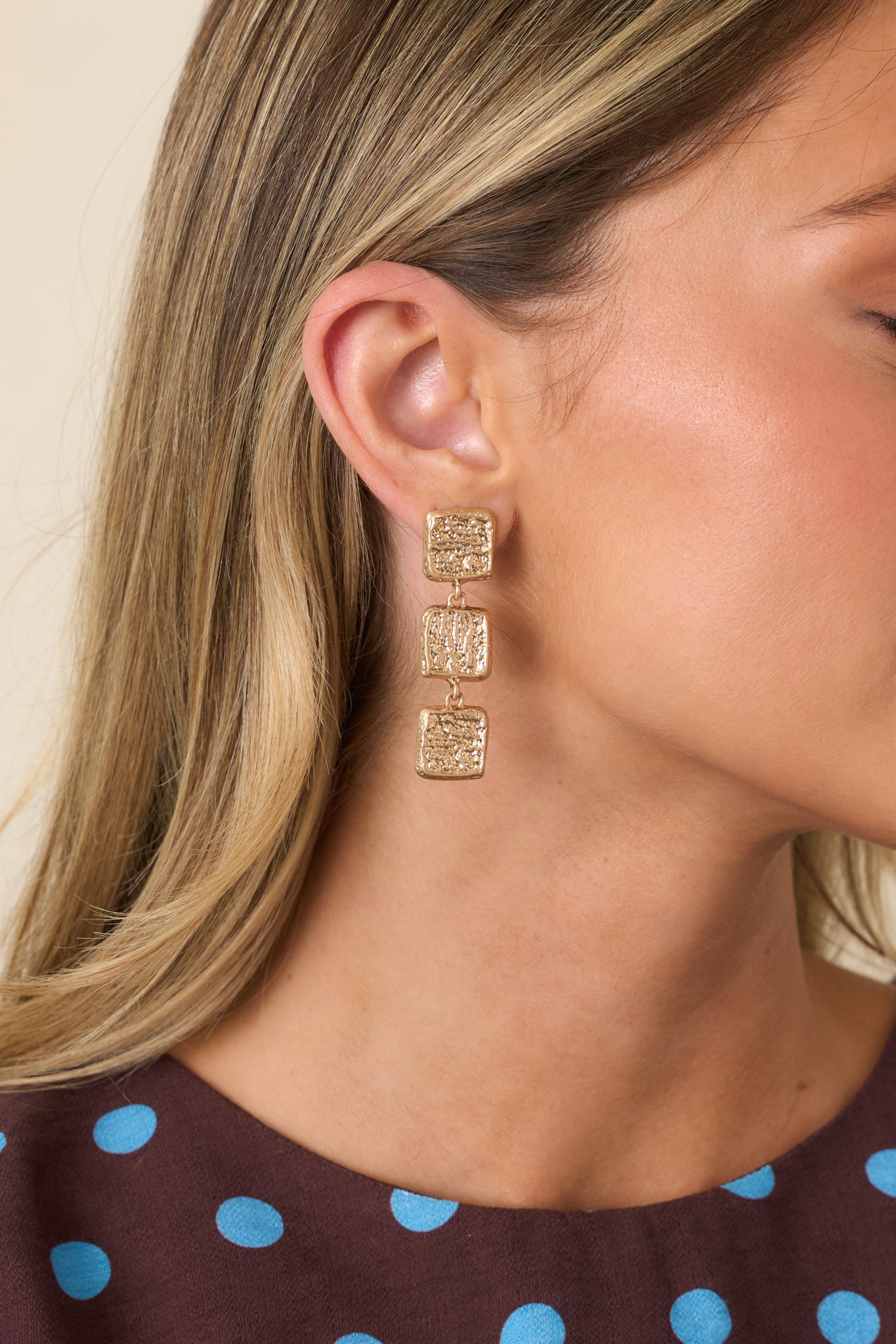 Gold drop earrings featuring three textured square shapes linked together for a modern sculptural design.