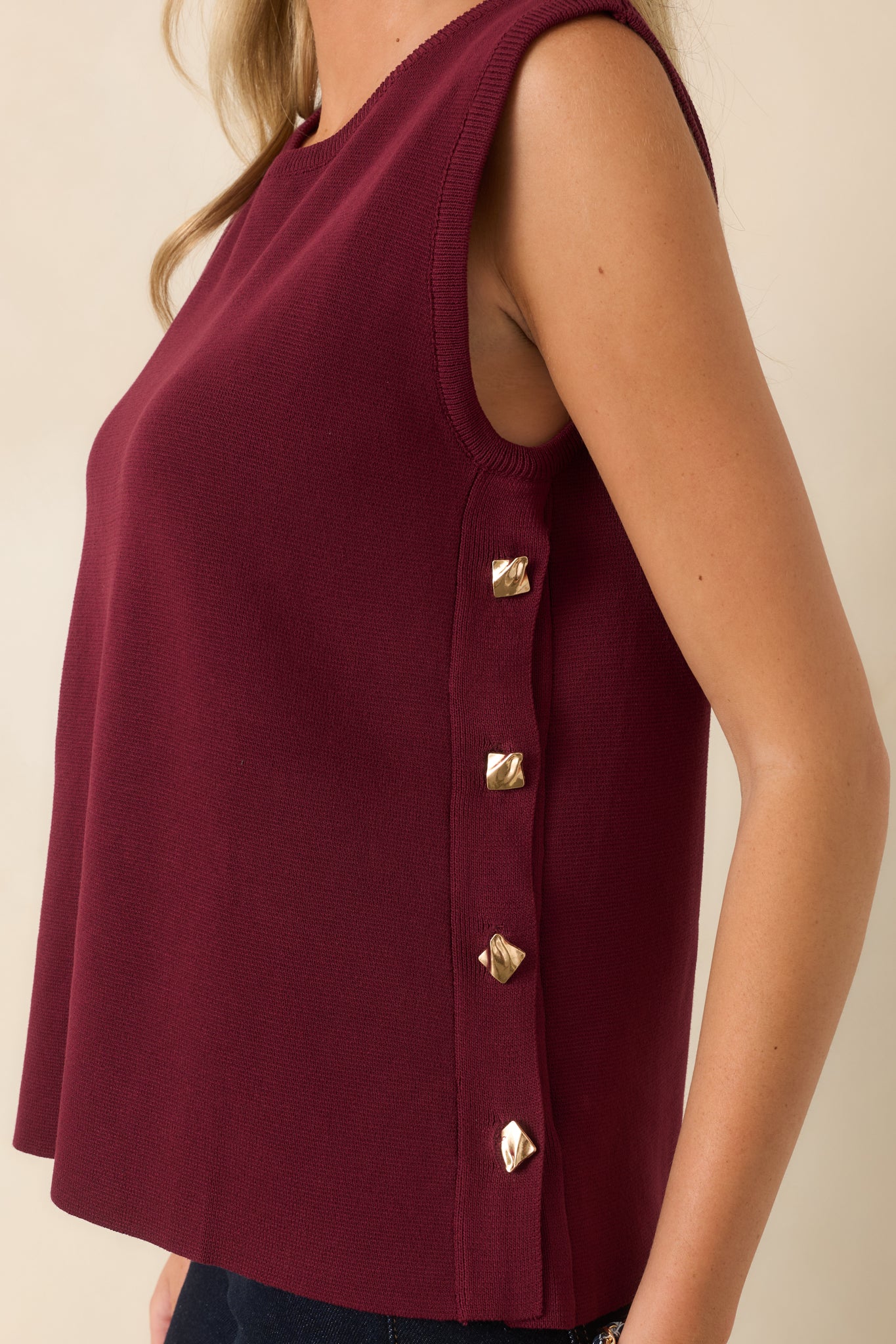 Close-up of the sweater knit featuring the functional gold-tone side buttons and smooth textured fabric.