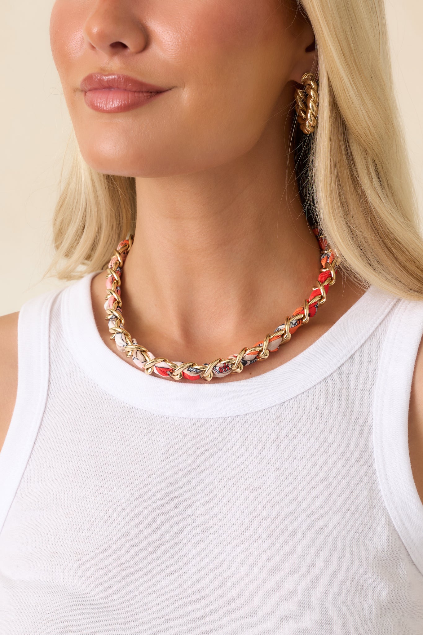 Gold-tone chain link necklace woven with orange multi-patterned scarf fabric, styled in a bold choker-length silhouette.