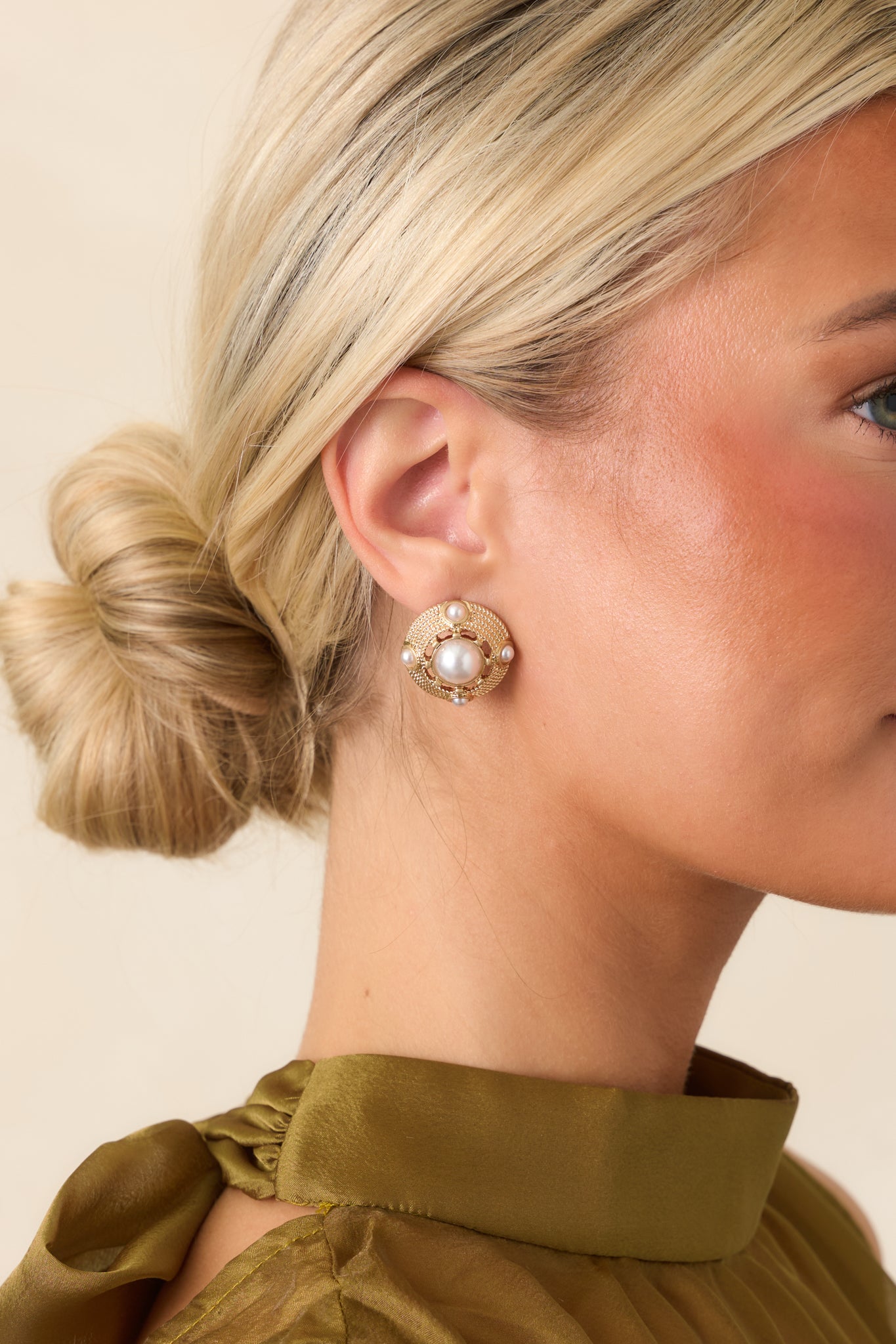 Gold-tone circular stud earrings featuring prominent faux pearl centers surrounded by smaller faux pearl accents in a dimensional setting.