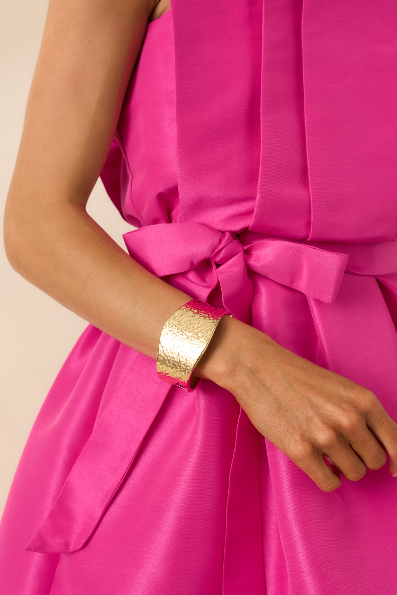 Cropped view of the gold-tone cuff bracelet showing the wide silhouette and hammered texture.