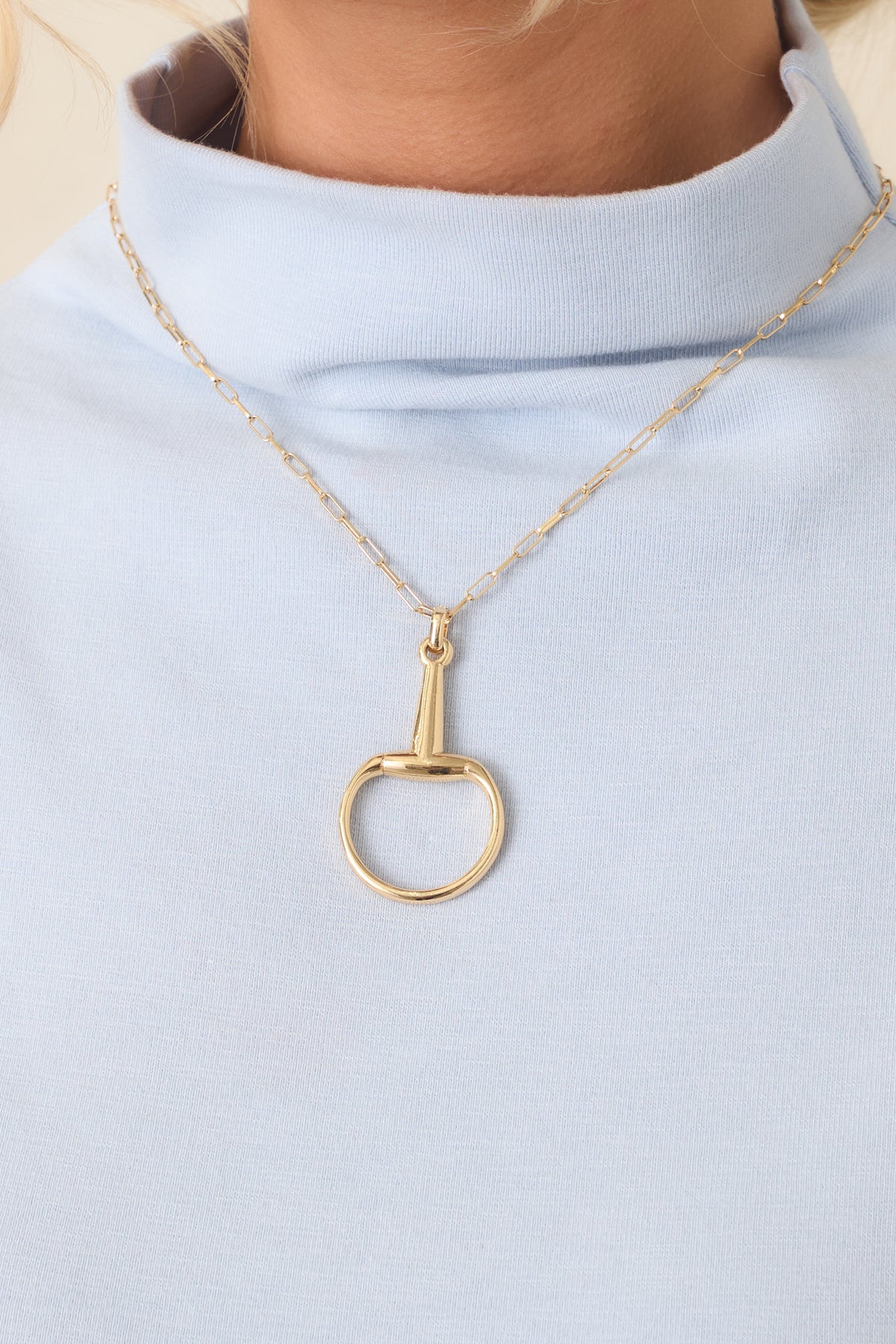 Delicate gold-tone necklace showcasing its sleek elongated links and distinctive circular pendant.