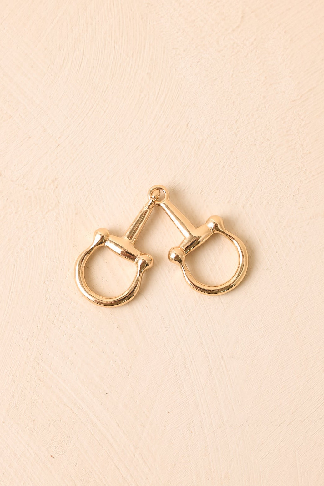Gold-tone scarf ring with two interlocking horsebit details and a sleek, polished surface.