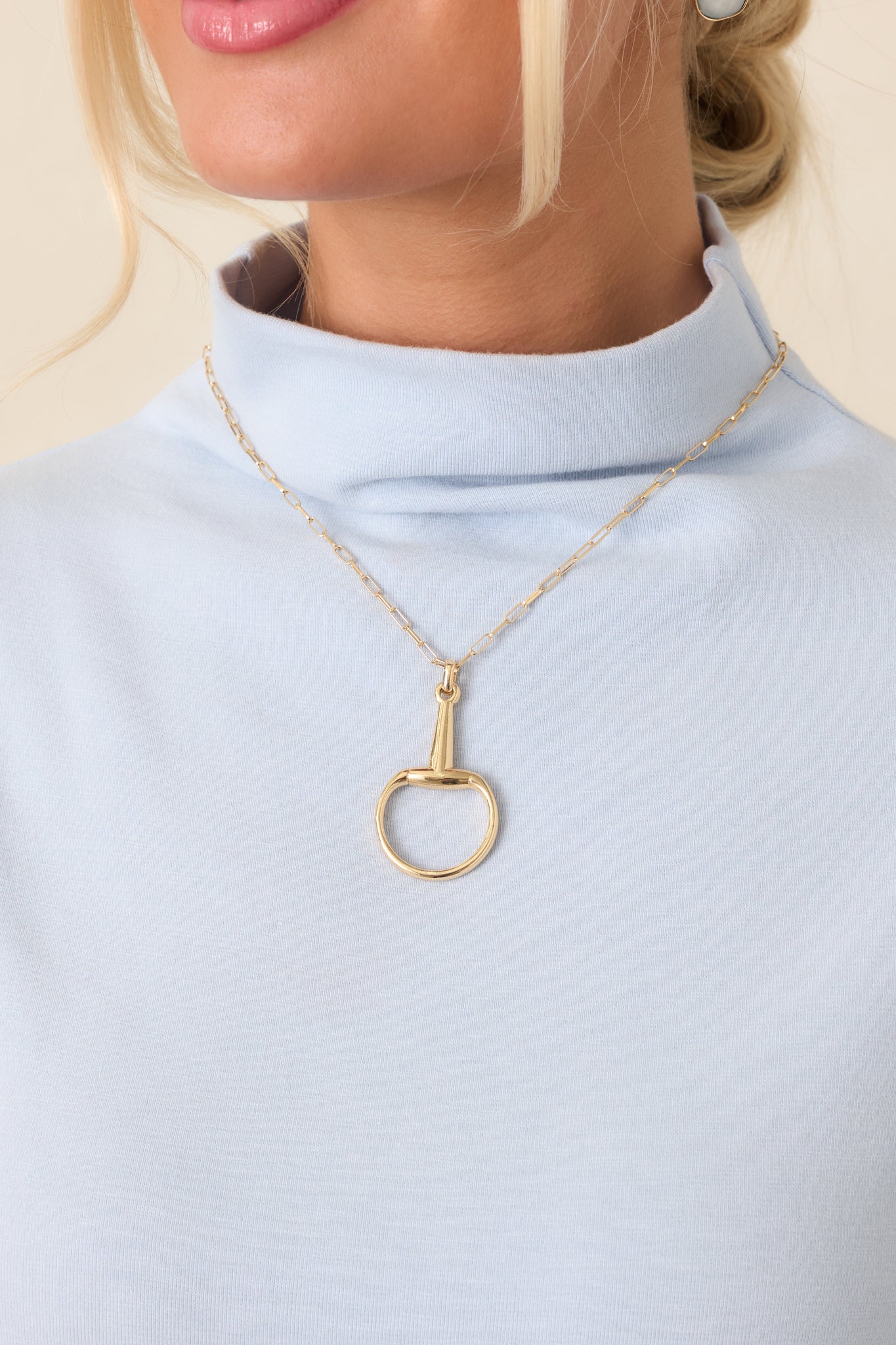 Gold-tone necklace with an elongated-link chain and open circular horsebit-inspired pendant.