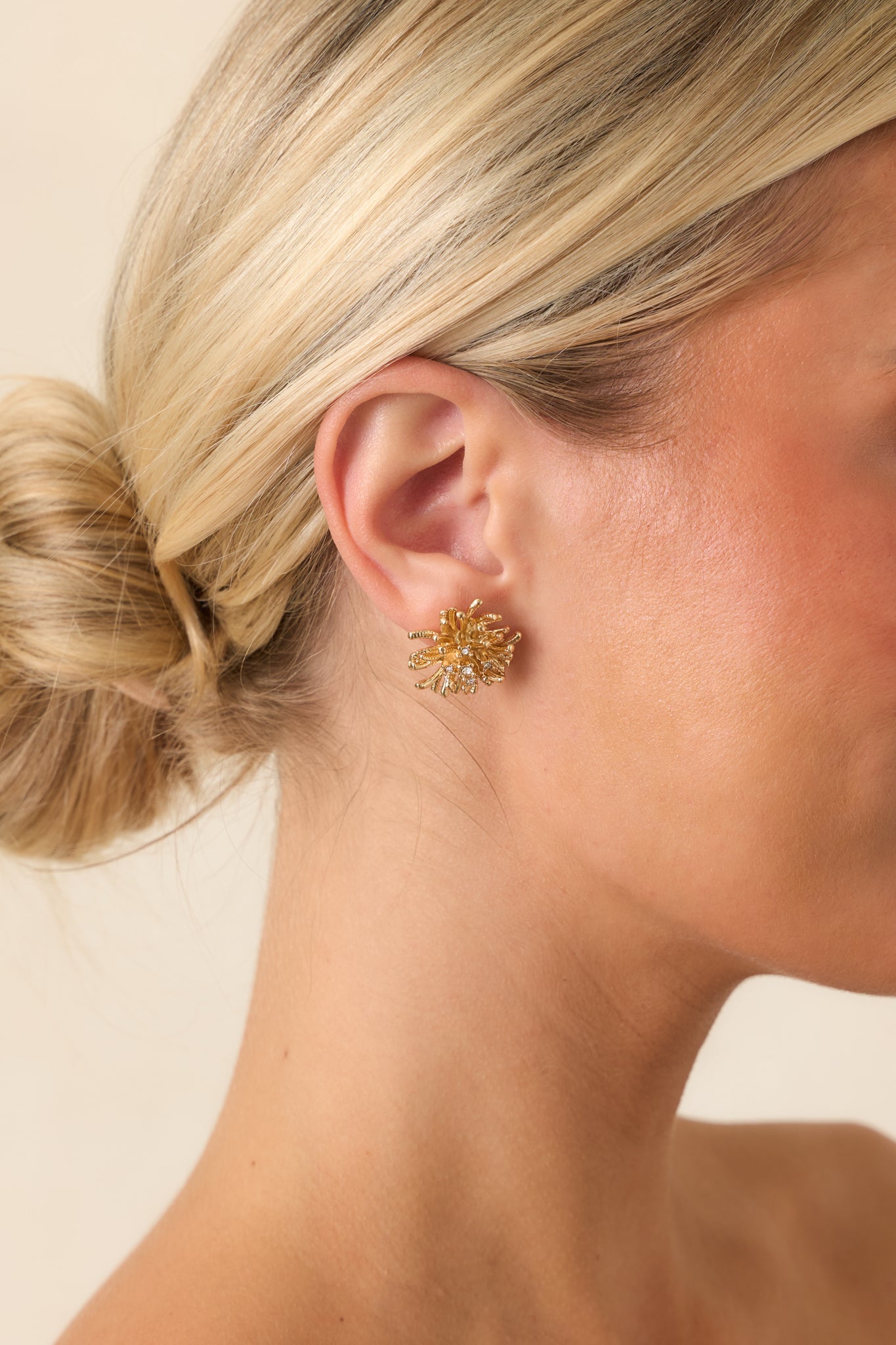 Gold-tone earrings featuring a sculptural freeform design with curved strands and delicate crystal accents for an artistic, modern finish.