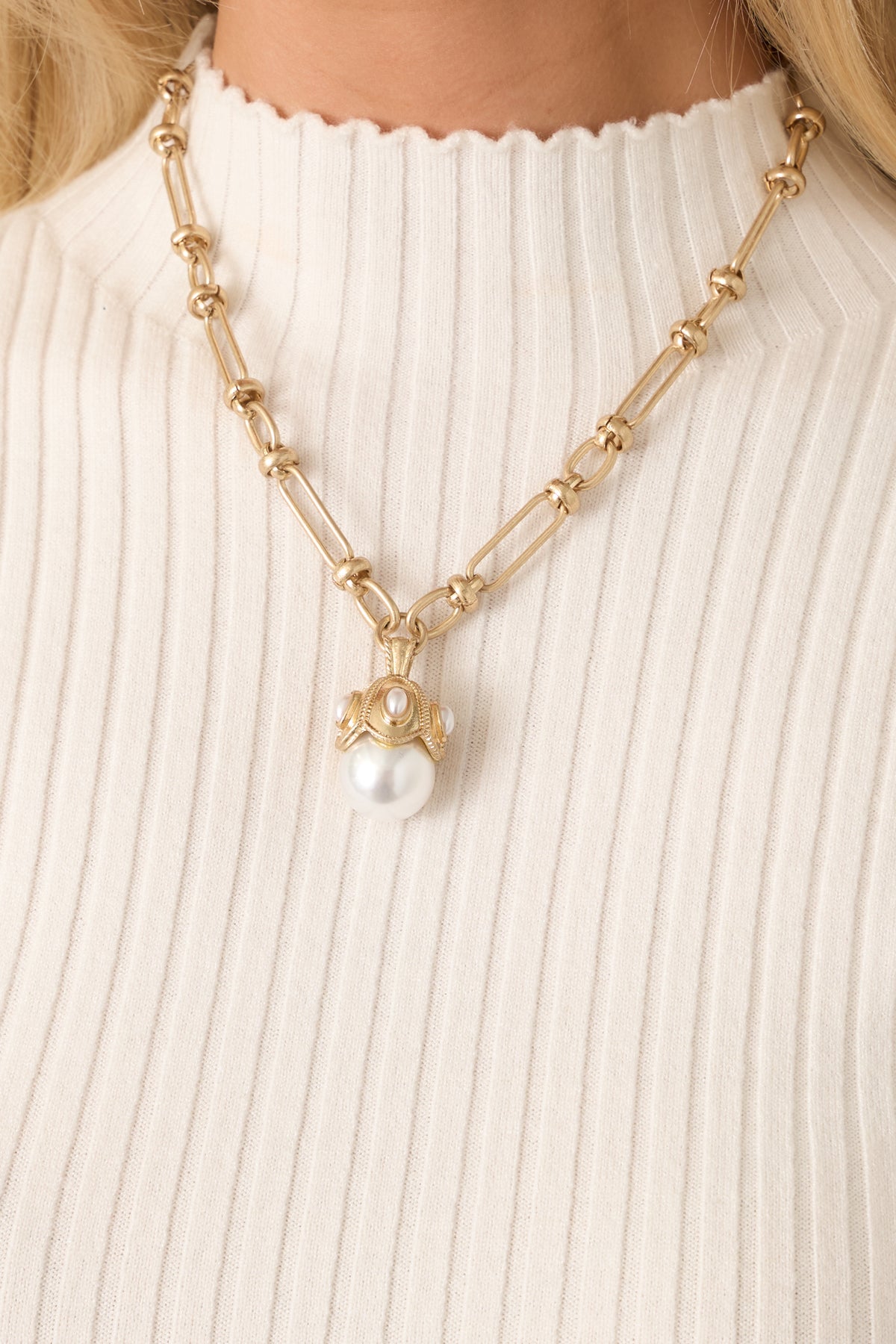 Gold-tone link necklace featuring alternating elongated and oval links with a luminous pearl pendant and ornate cap.