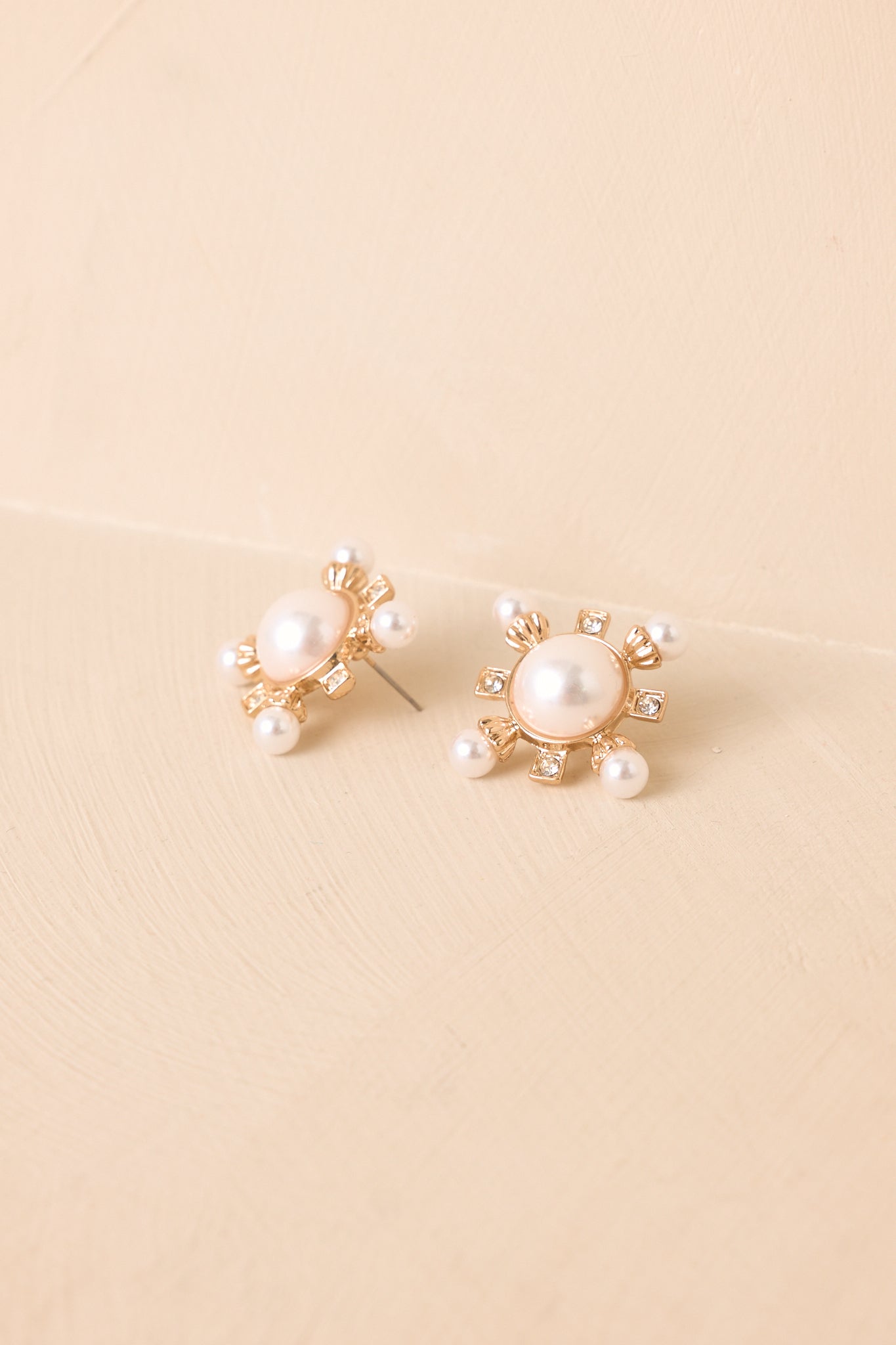 Gold-tone stud earrings featuring faux pearls, delicate pearl accents, and shimmering crystal embellishments.