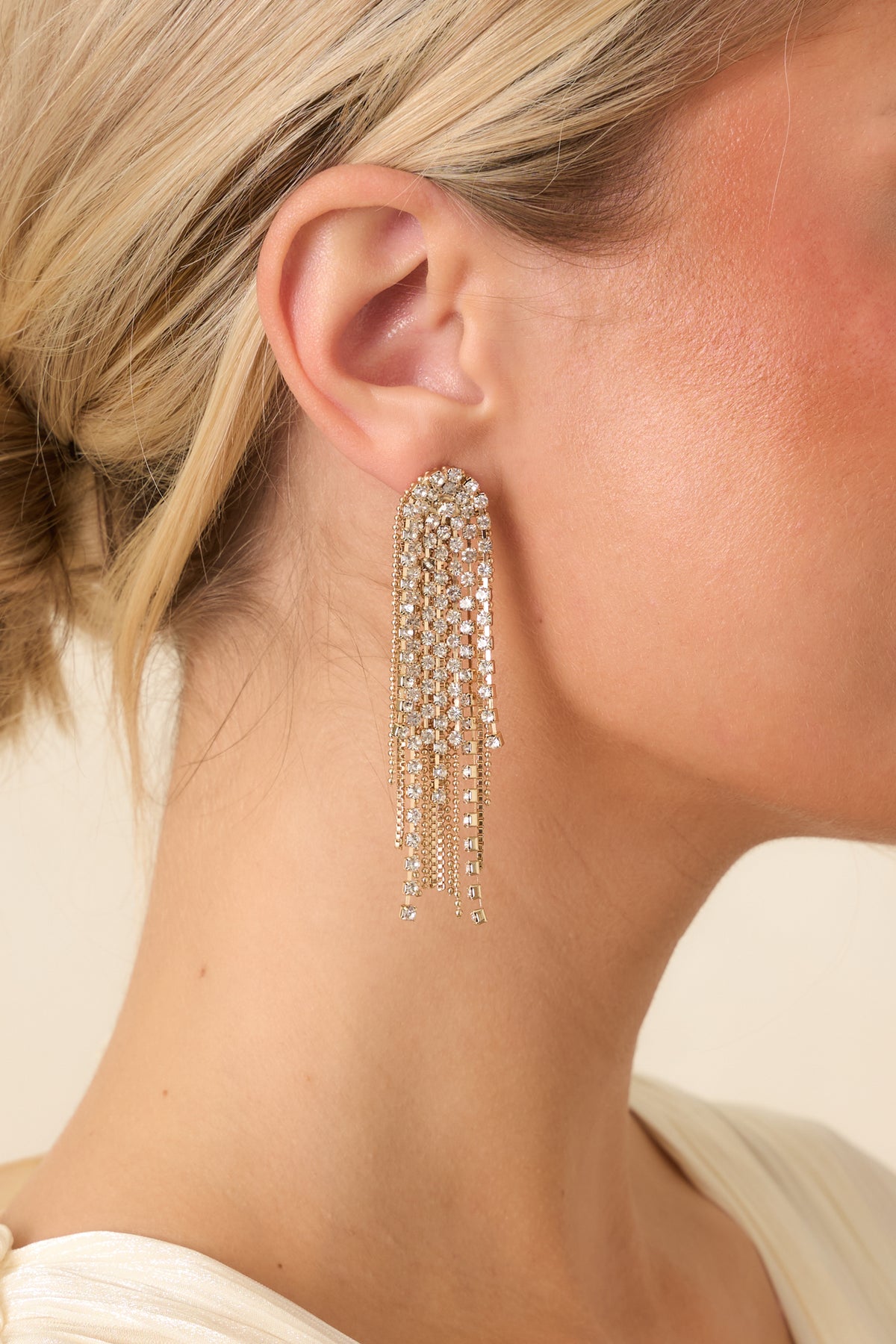 Gold-tone statement earrings with crystal-encrusted round studs and cascading clear rhinestone fringe.