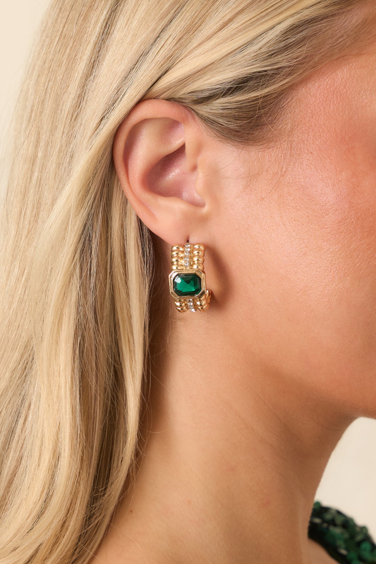 Gold-tone ribbed hoop earrings with faceted emerald green centers and sparkling clear crystal accents.